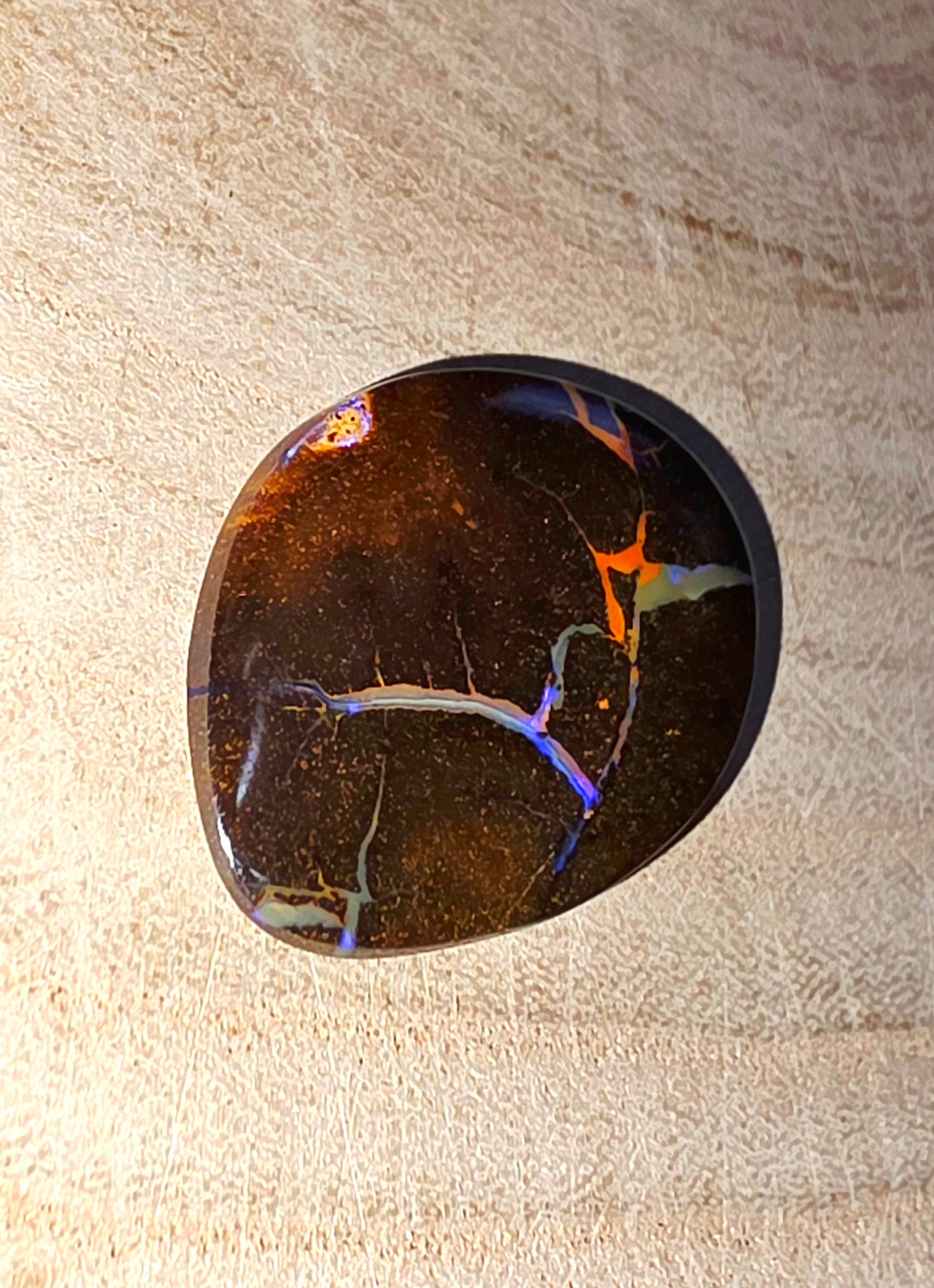 Polished stone with colourful marbled pattern on a beige surface
