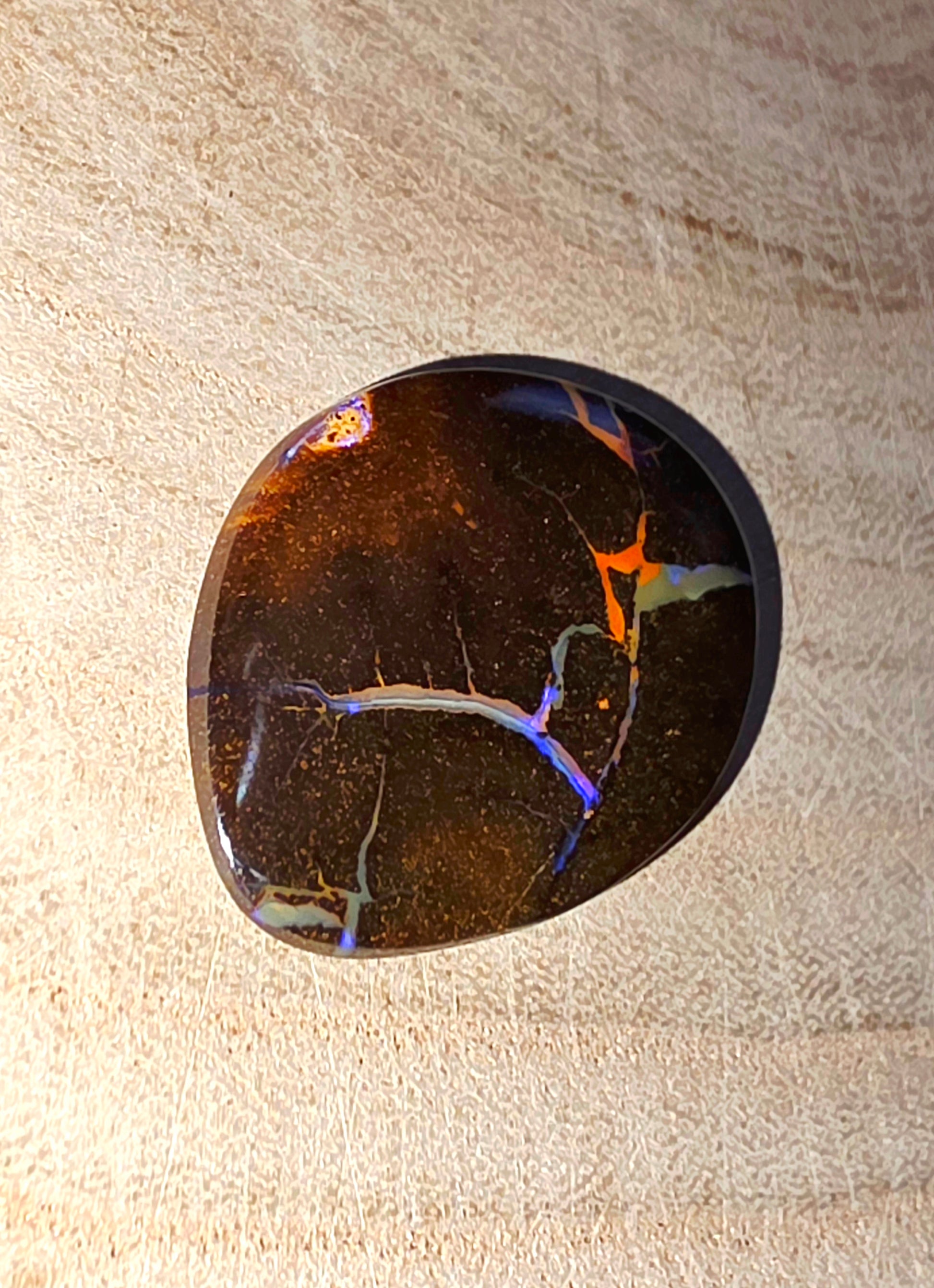 Polished stone with colourful marbled pattern on a beige surface