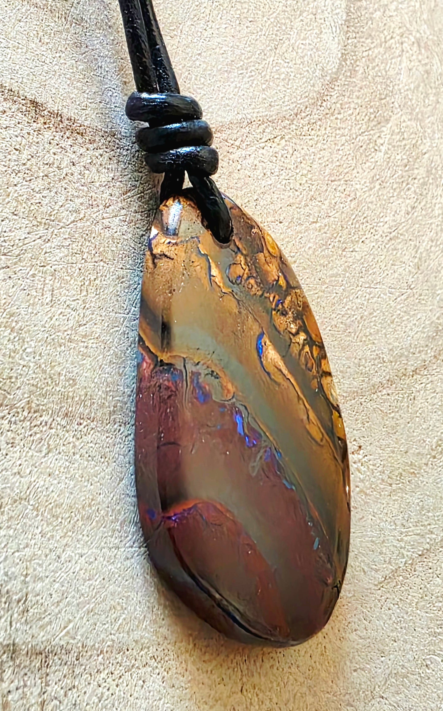 Opal pendant on a beige textured background 