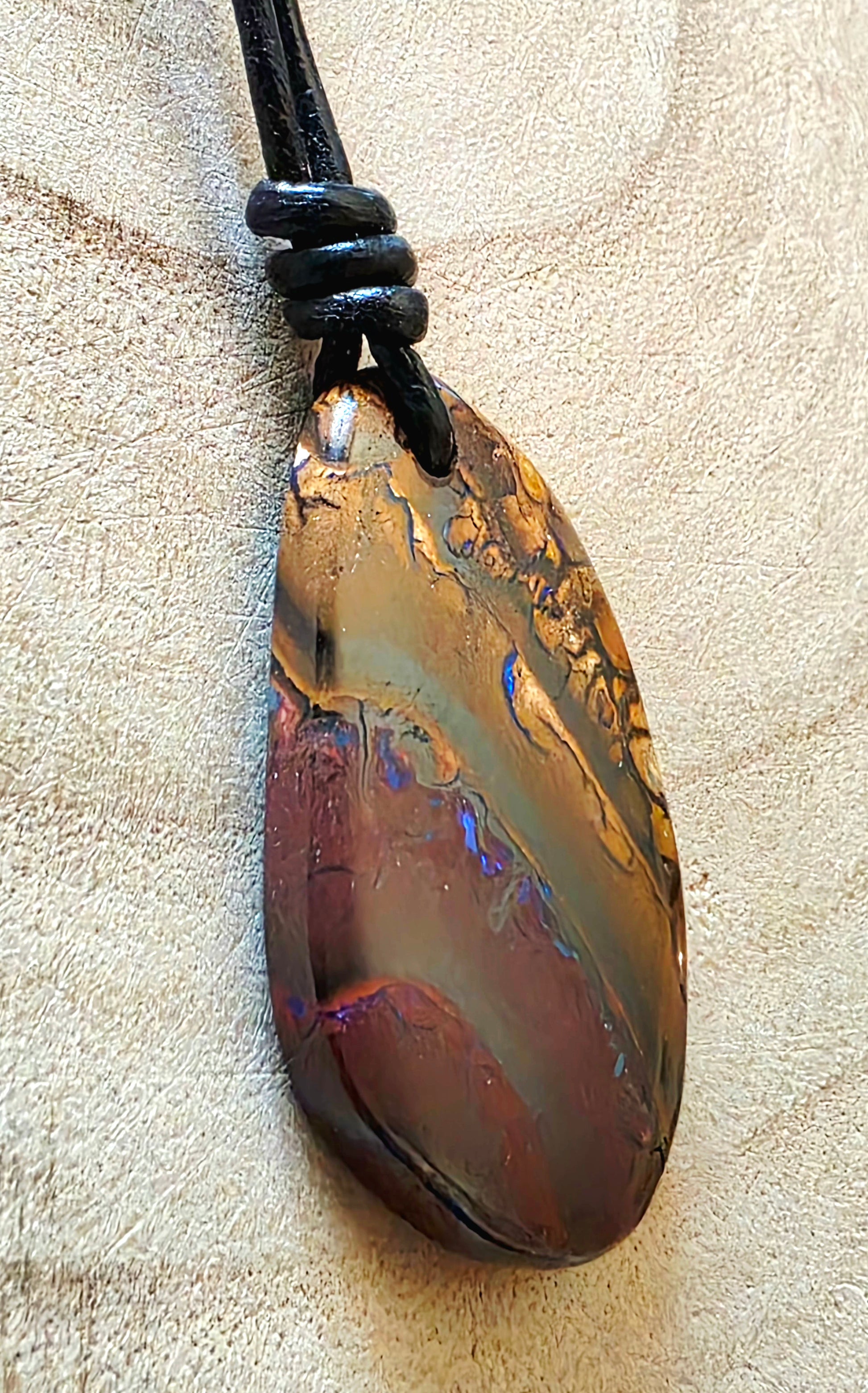 Opal pendant on a beige textured background 