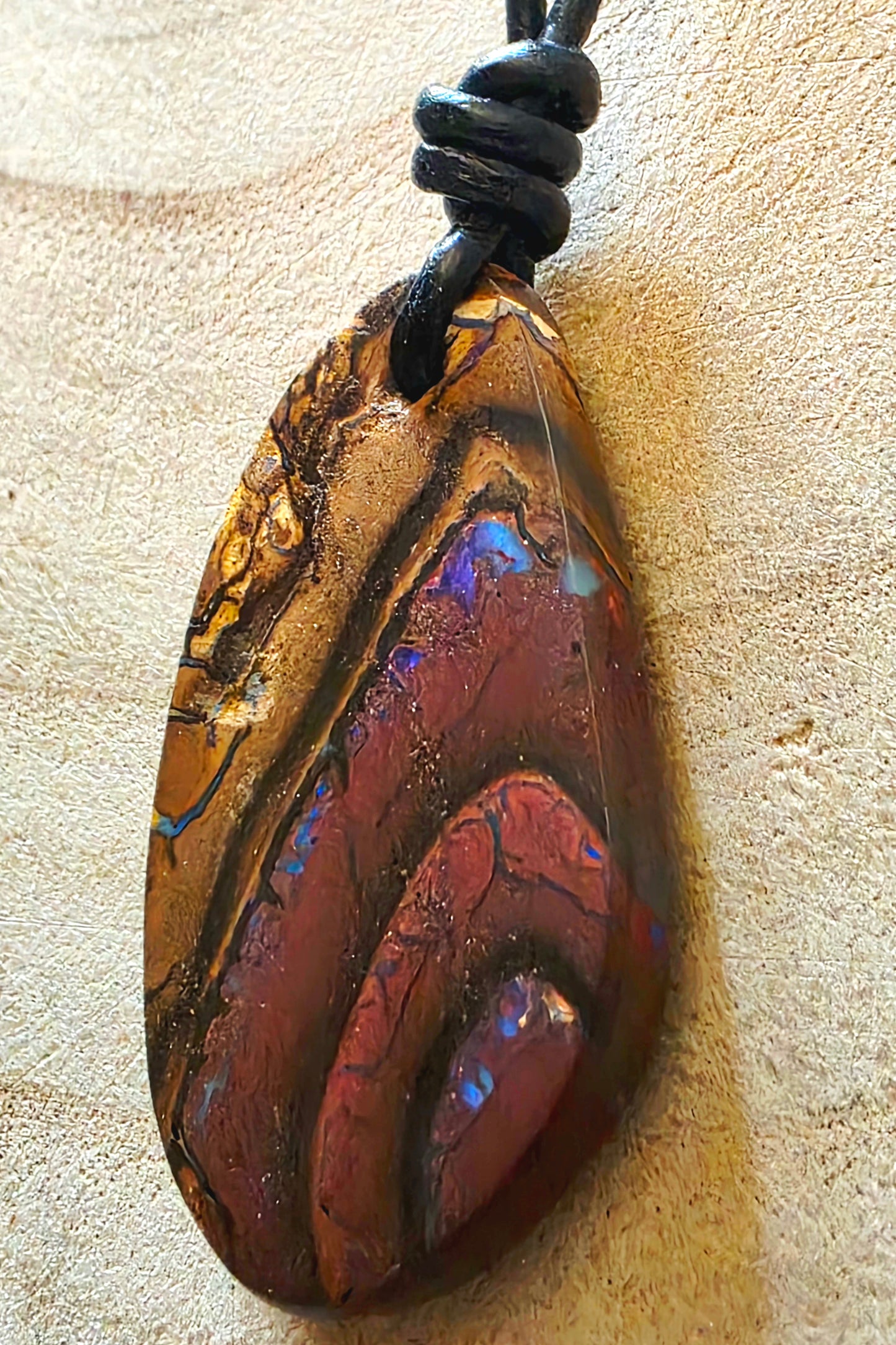 Multicoloured opal pendant on a beige background