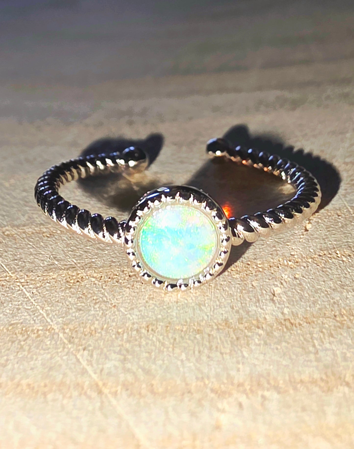Ring with opal stone and band on a beige surface