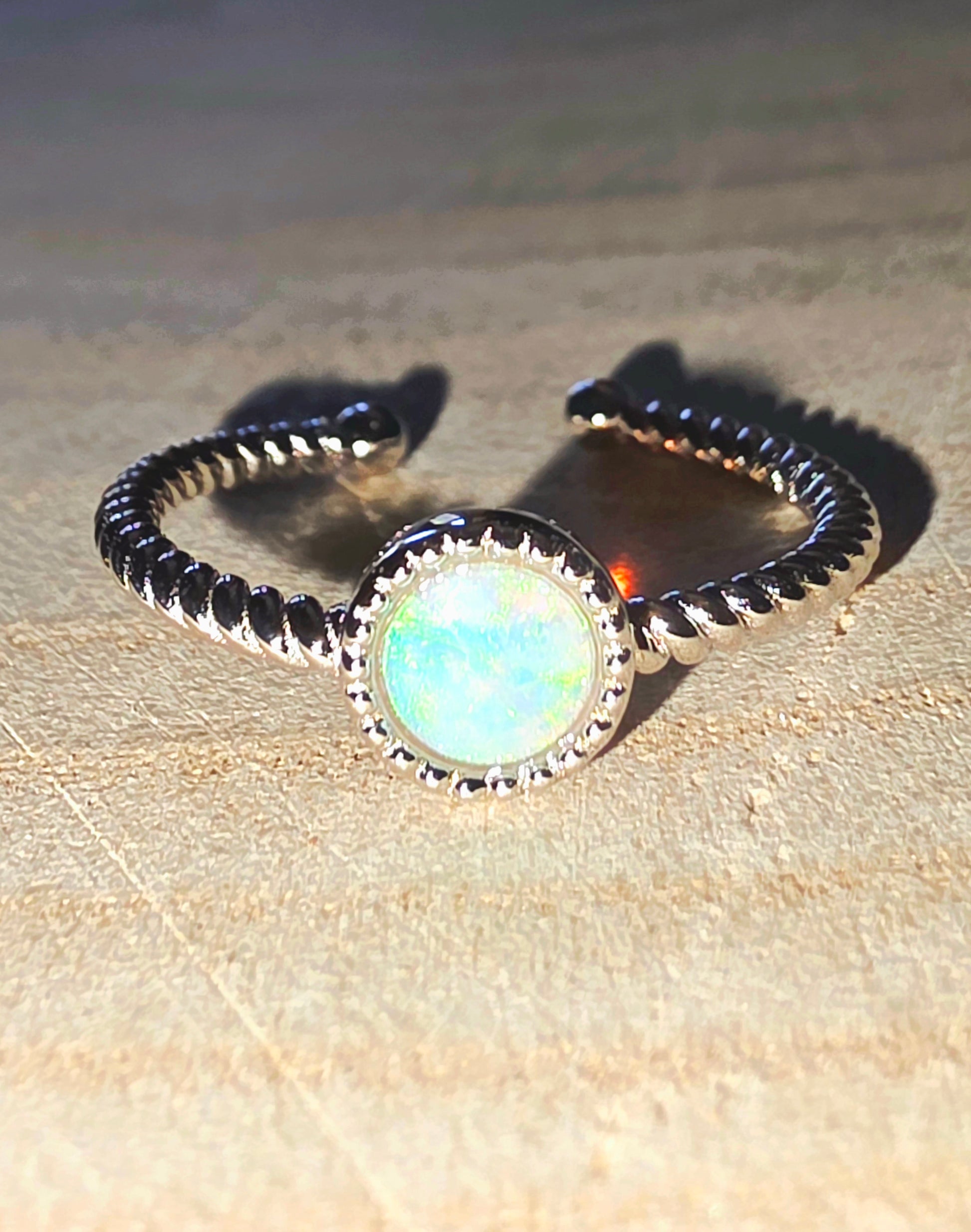 Ring with opal stone and band on a beige surface