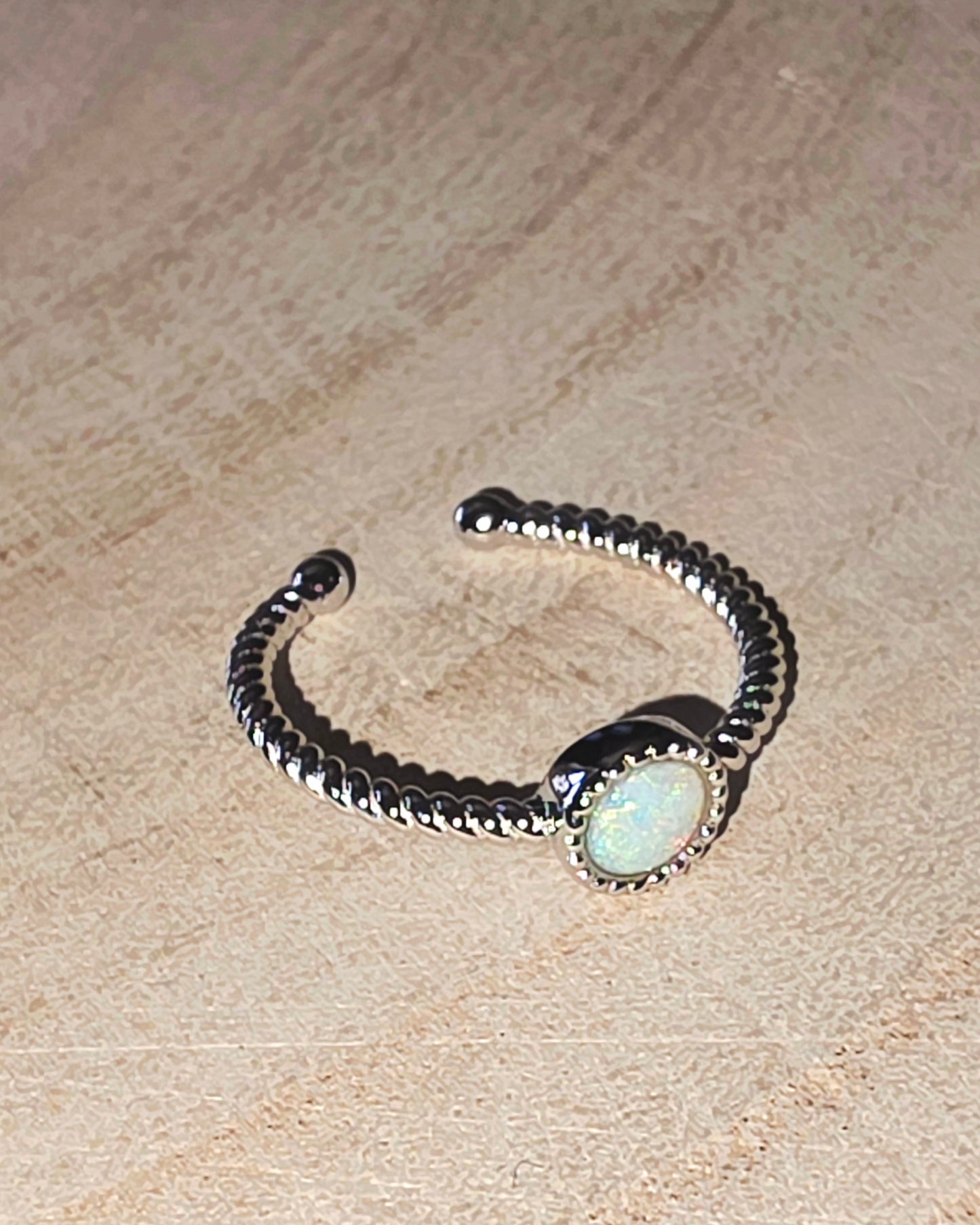 Silver ring with a central gemstone on a beige surface