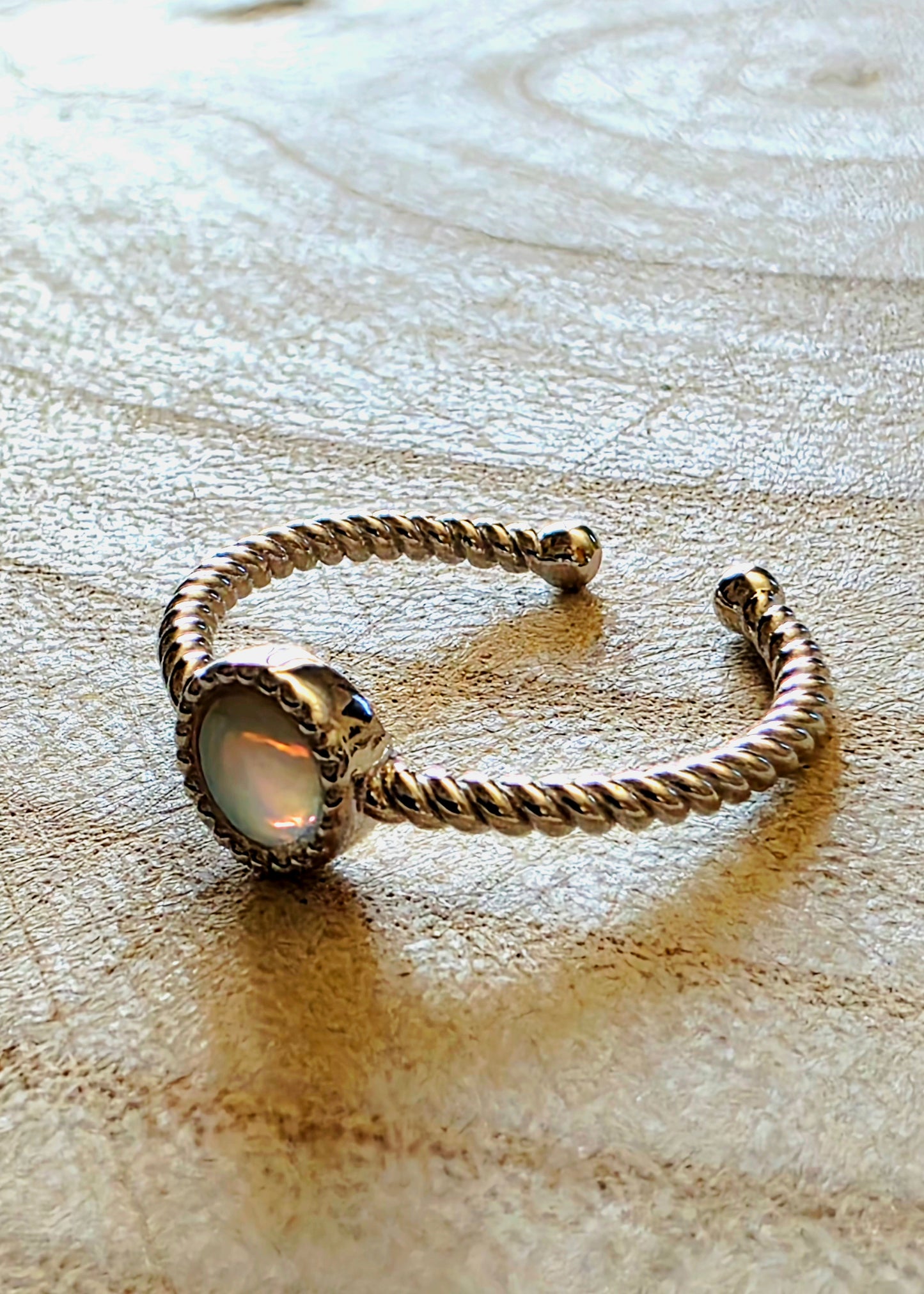 Silver ring with a central opal on a textured surface