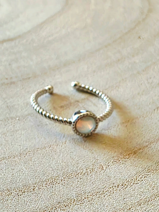 Silver ring with an opal on a textured beige surface