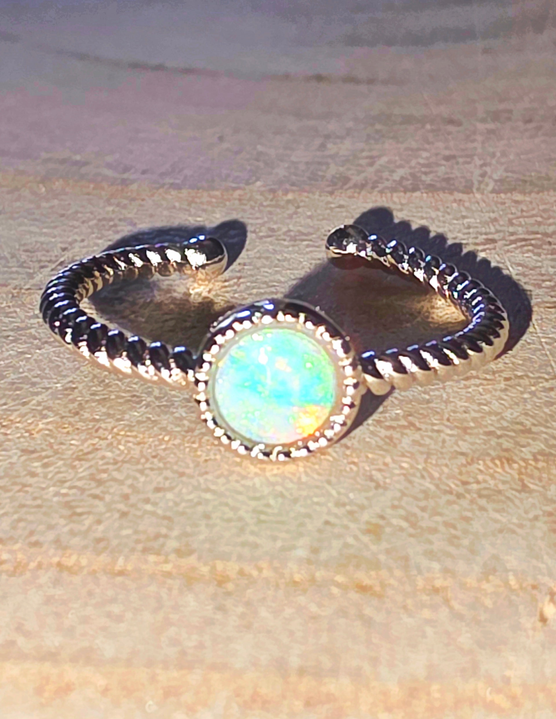 Silver ring with a central opal on a beige fabric background