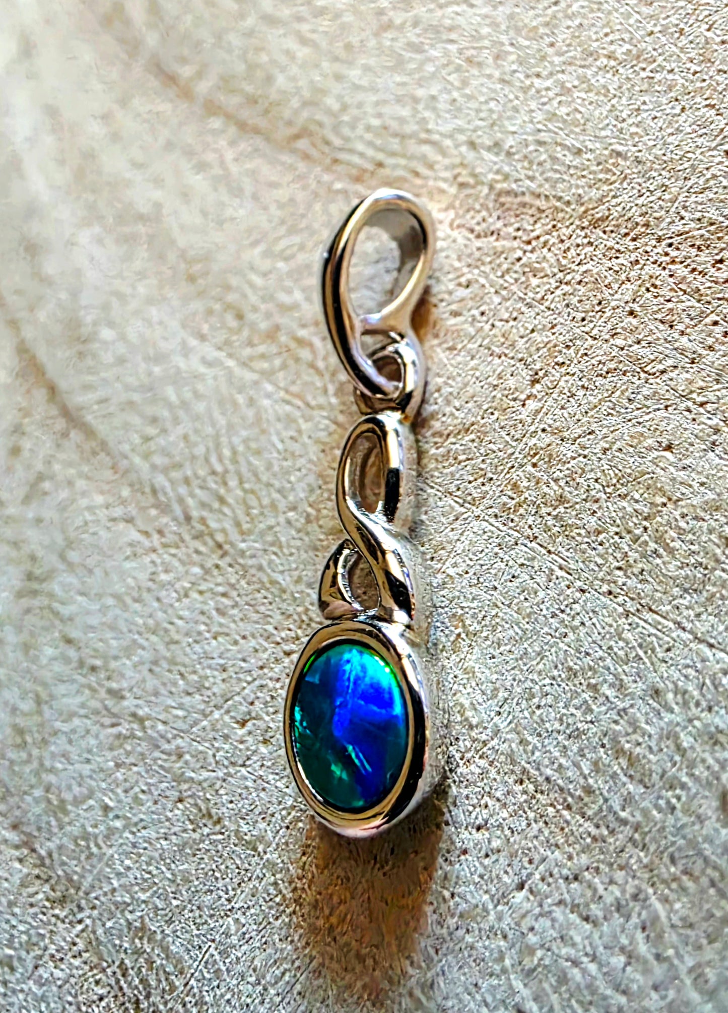 Silver pendant with a blue gemstone on a textured beige surface