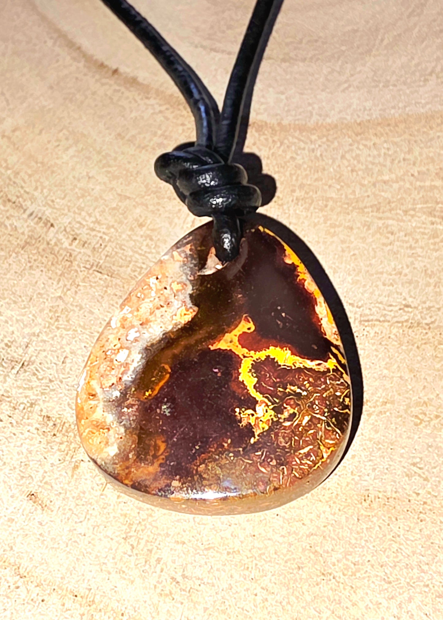 Opal pendant on a black cord against a beige background
