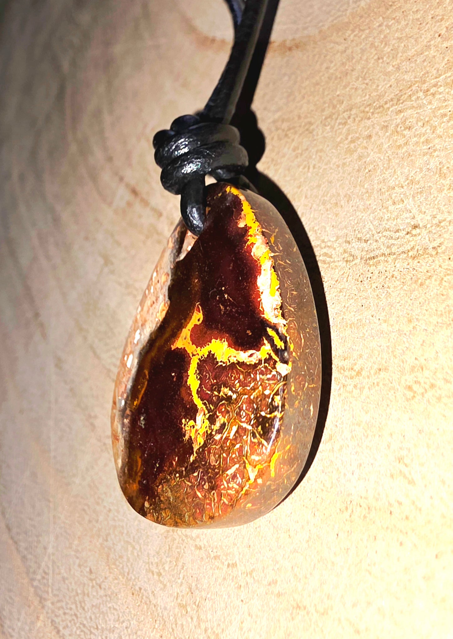 Teardrop-shaped pendant with a textured surface on a beige background