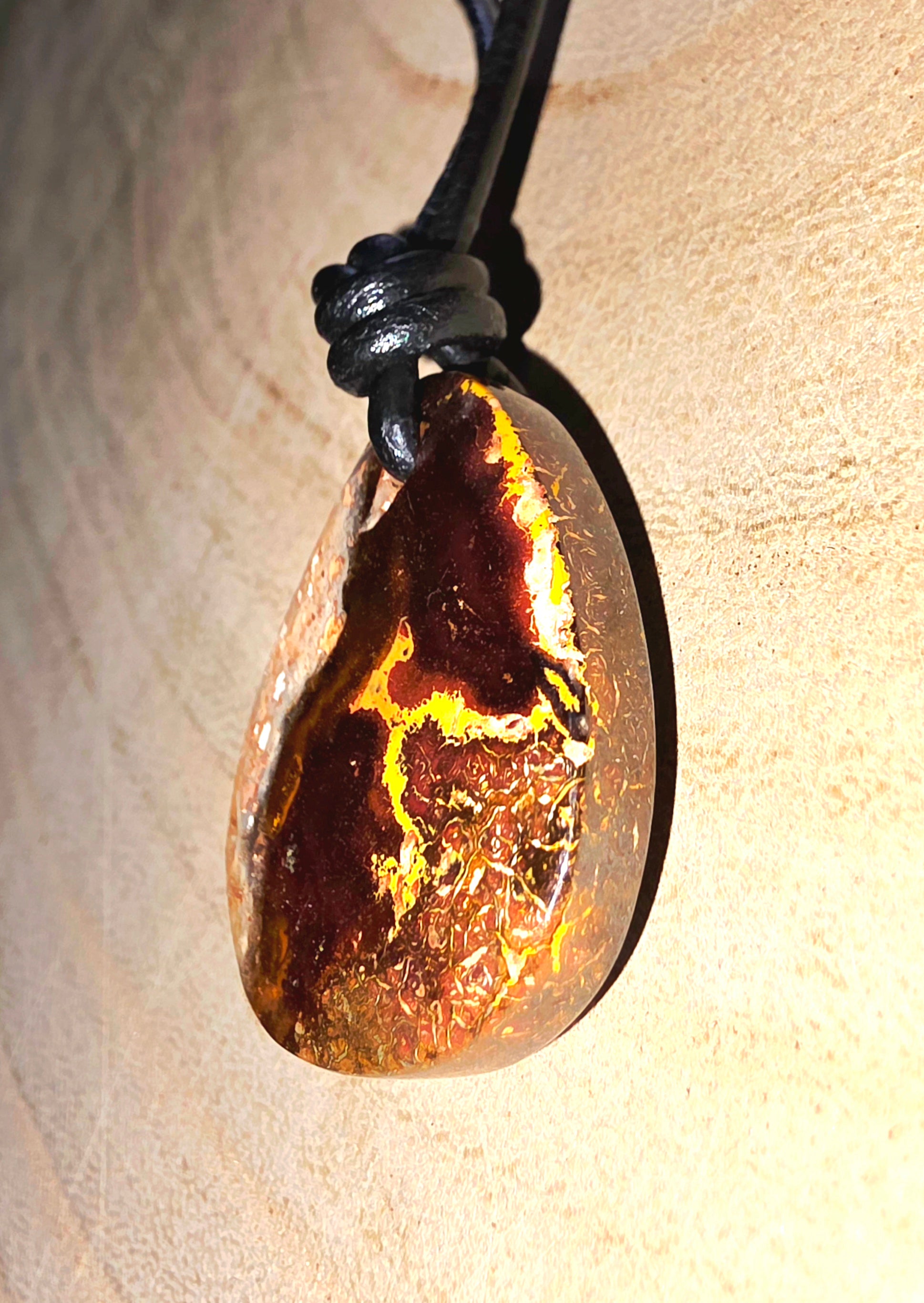 Teardrop-shaped pendant with a textured surface on a beige background