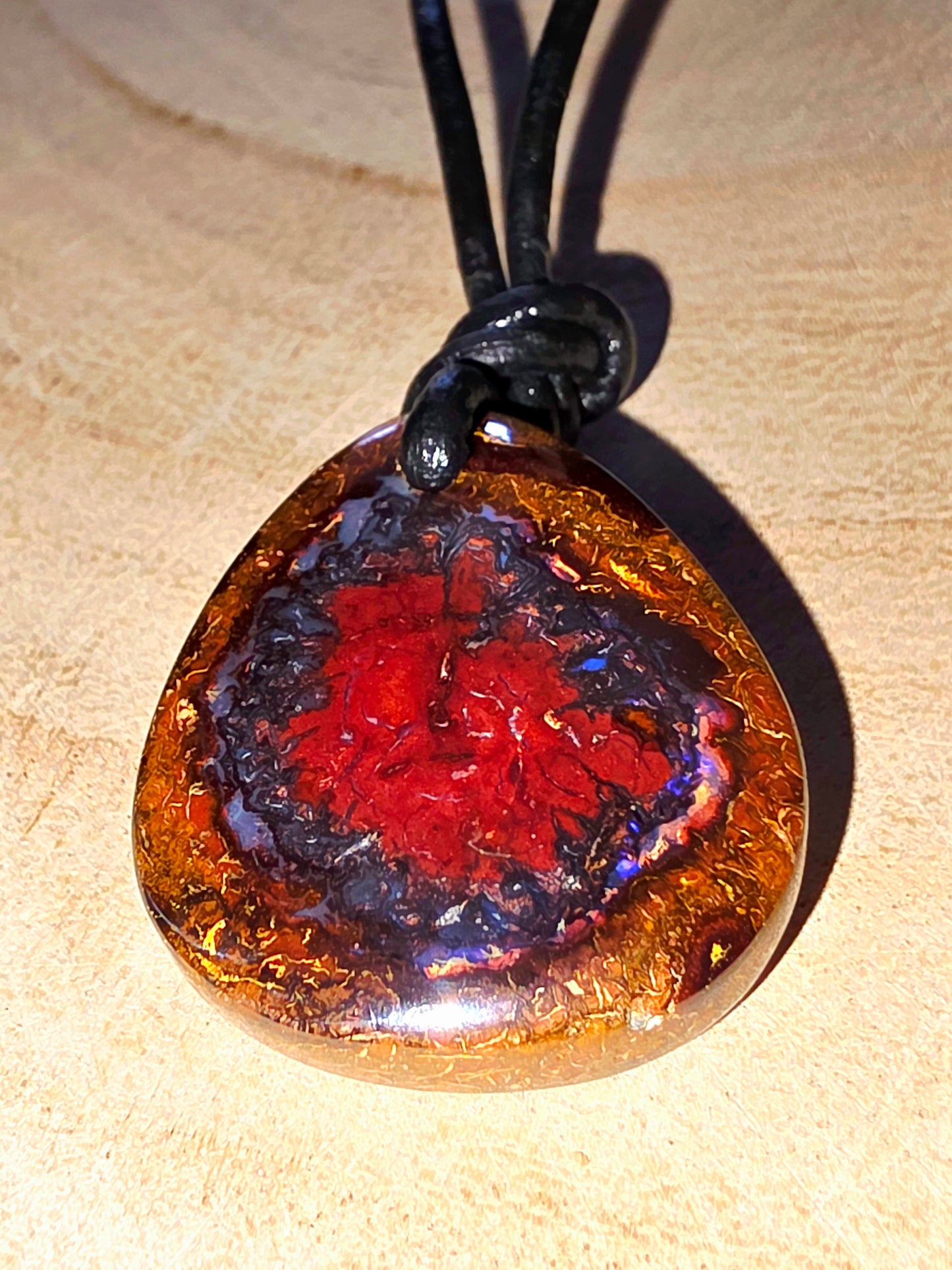 Necklace with a round pendant featuring a red and blue interior on a beige background