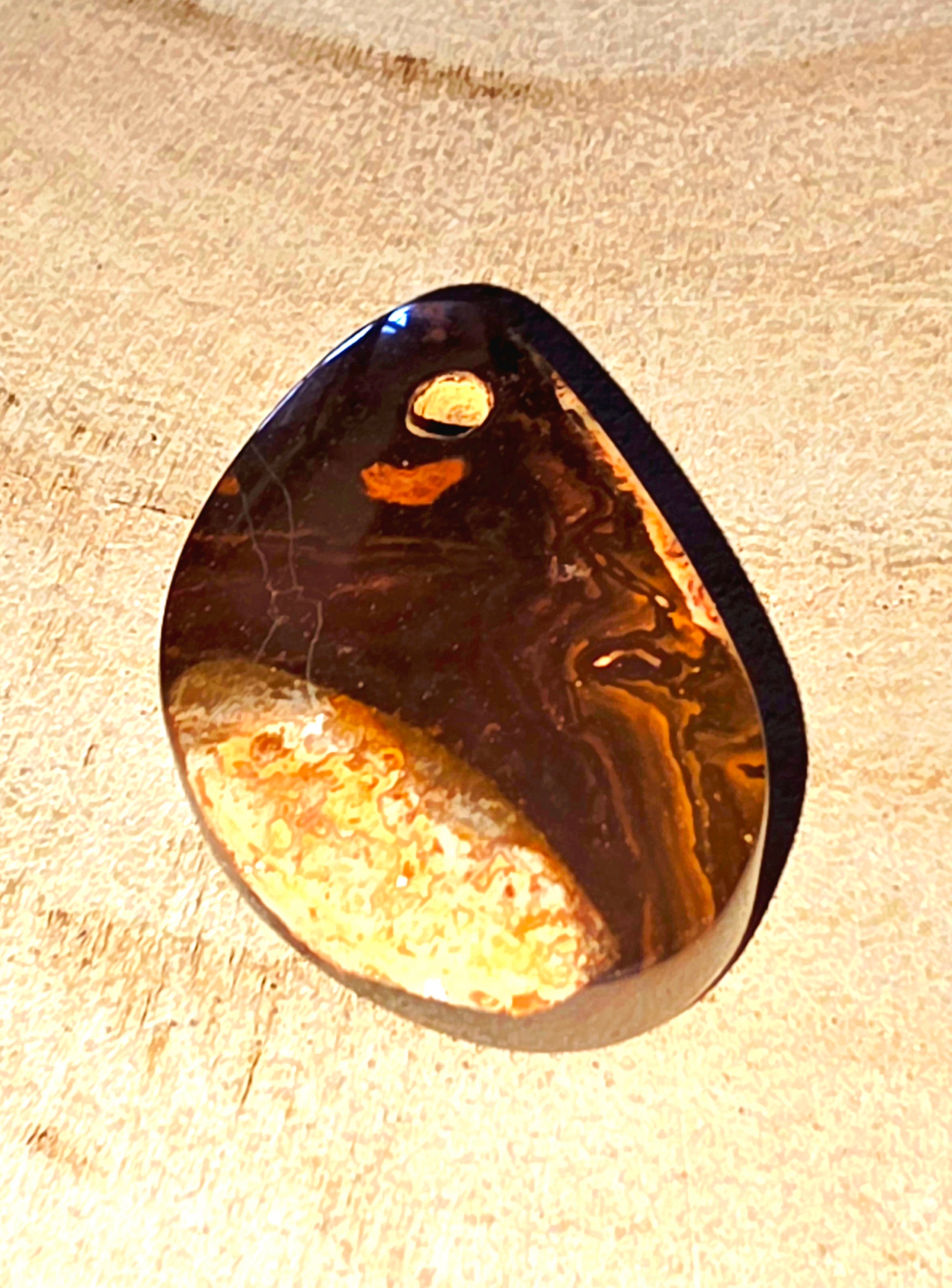 Teardrop-shaped opal stone on a beige fabric background