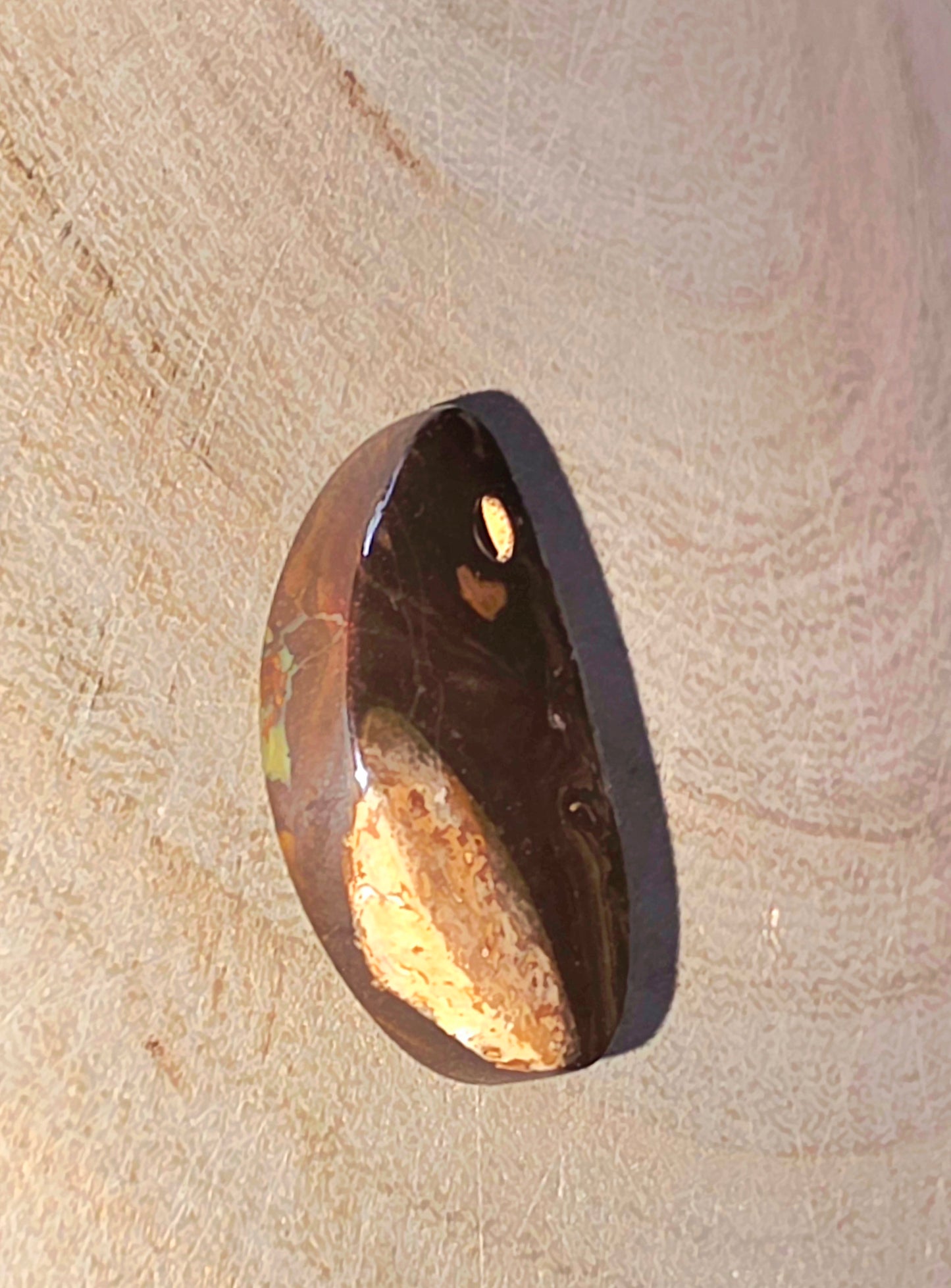 Brown opal stone with a gold interior on a beige surface