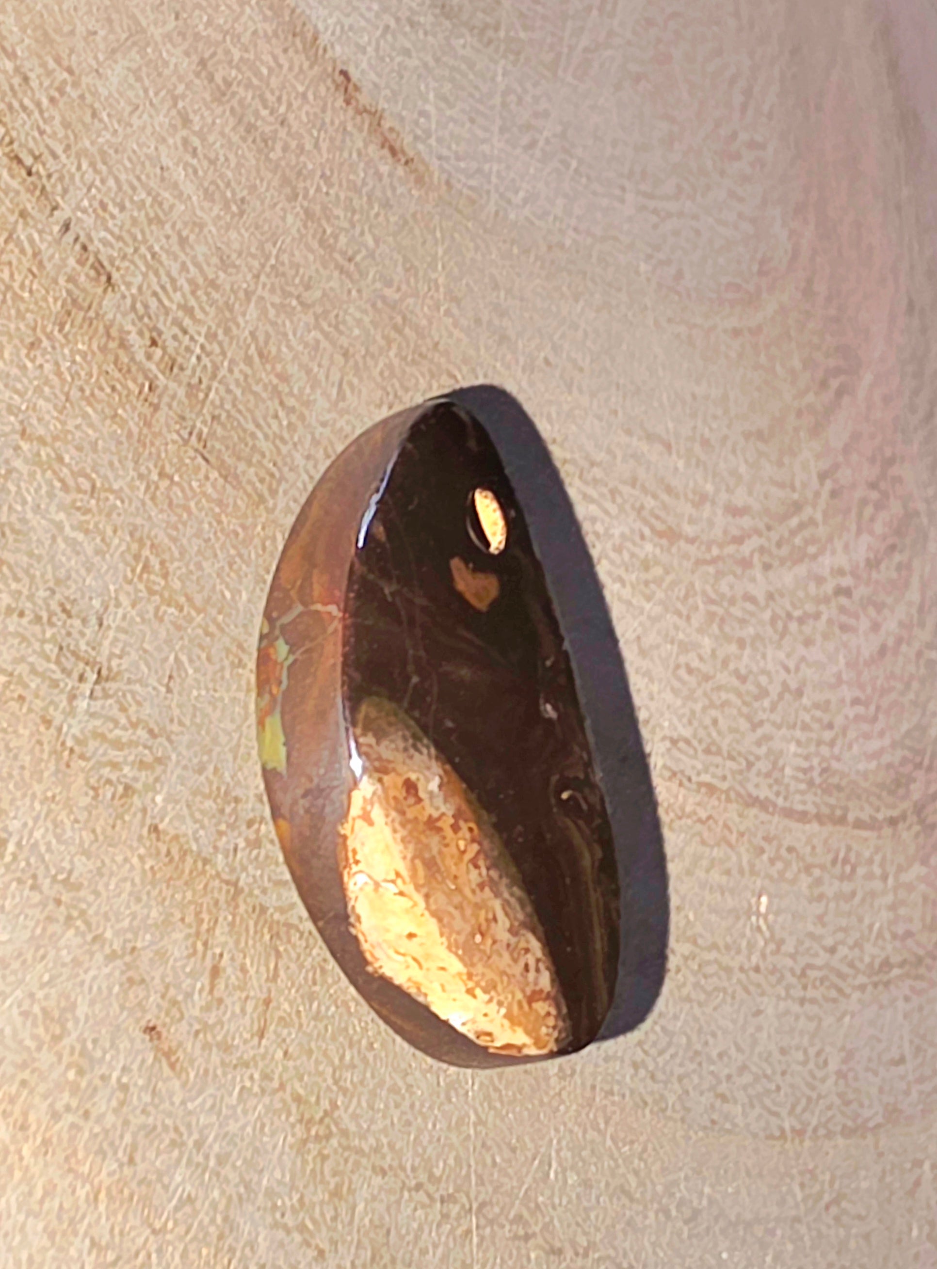 Brown opal stone with a gold interior on a beige surface