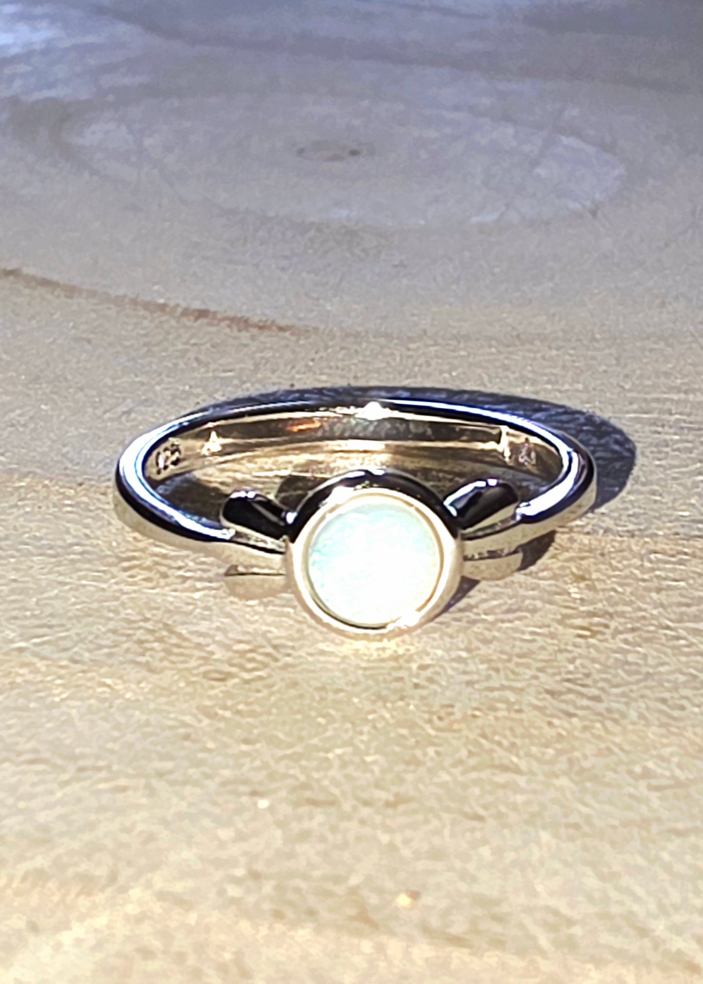 Silver ring with a white opal gemstone on a wood surface