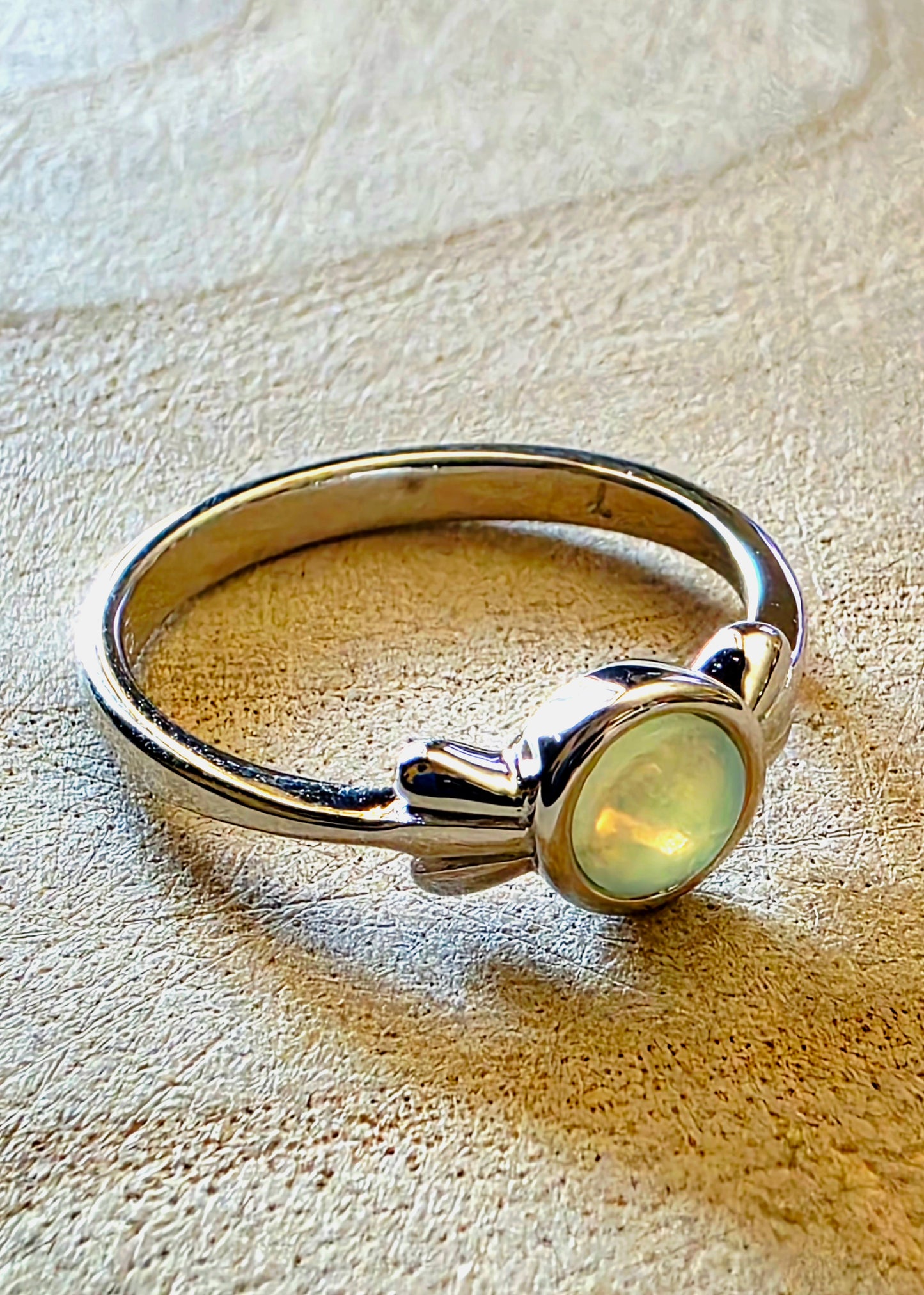 Silver ring with a white opal gemstone on a wood surface