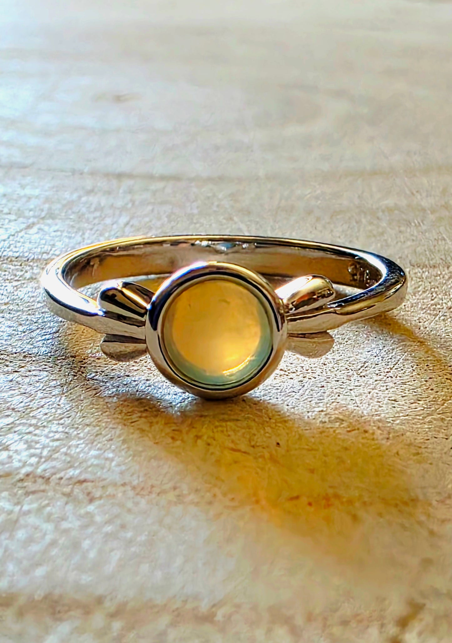 Silver ring with a white opal gemstone on a wood surface