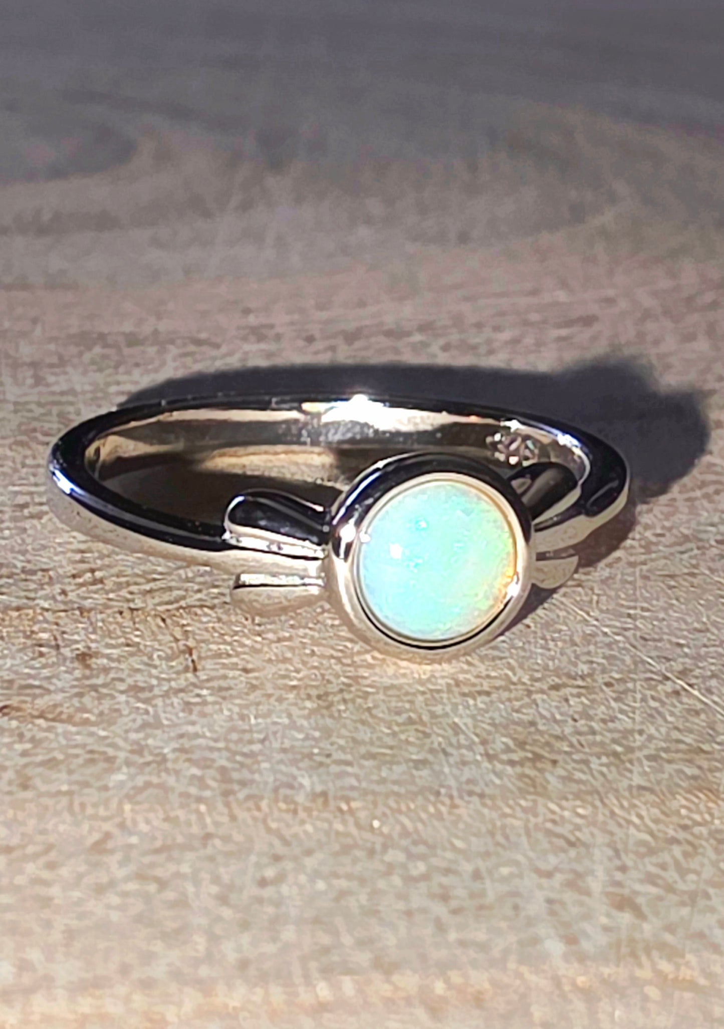 Silver ring with a light opal gemstone on a wooden surface
