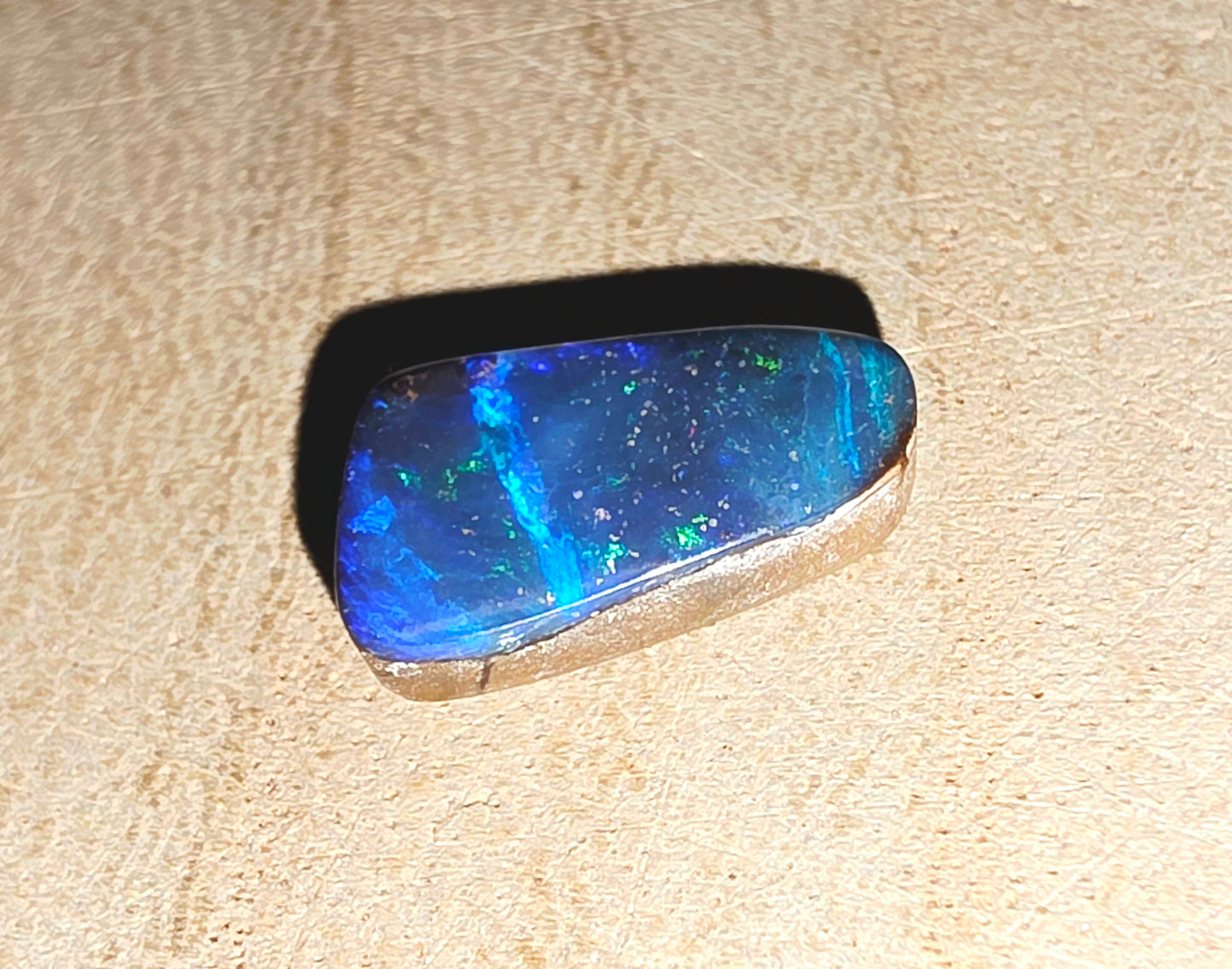 Blue opal stone on a beige wood background
