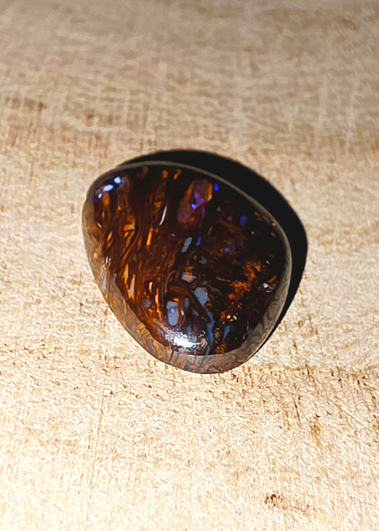 Polished opal stone on a textured beige surface