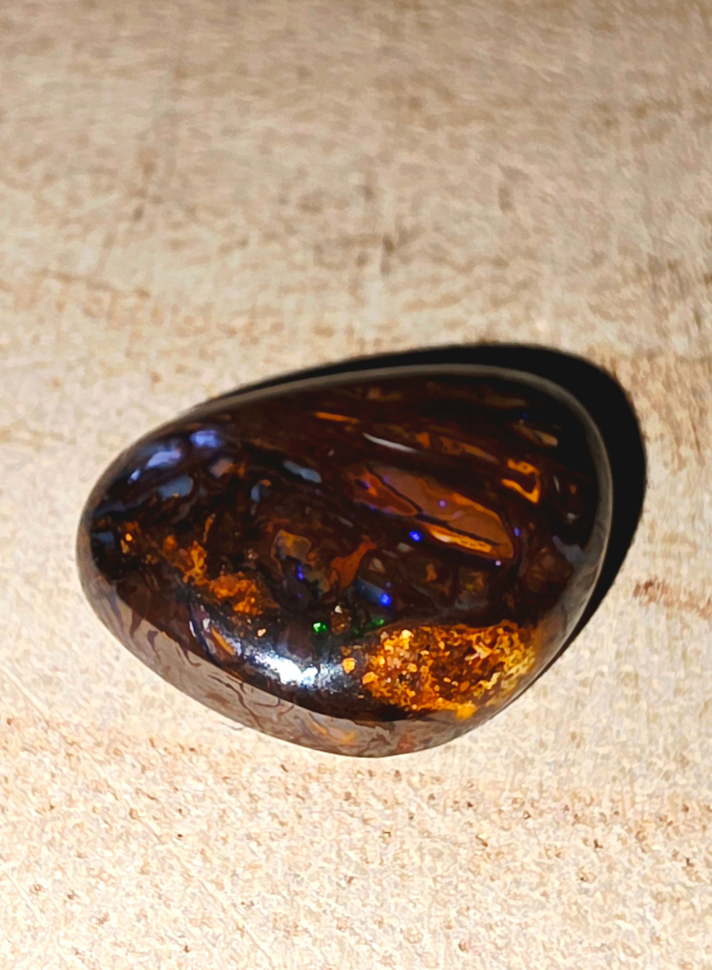 Polished opal stone on a beige surface