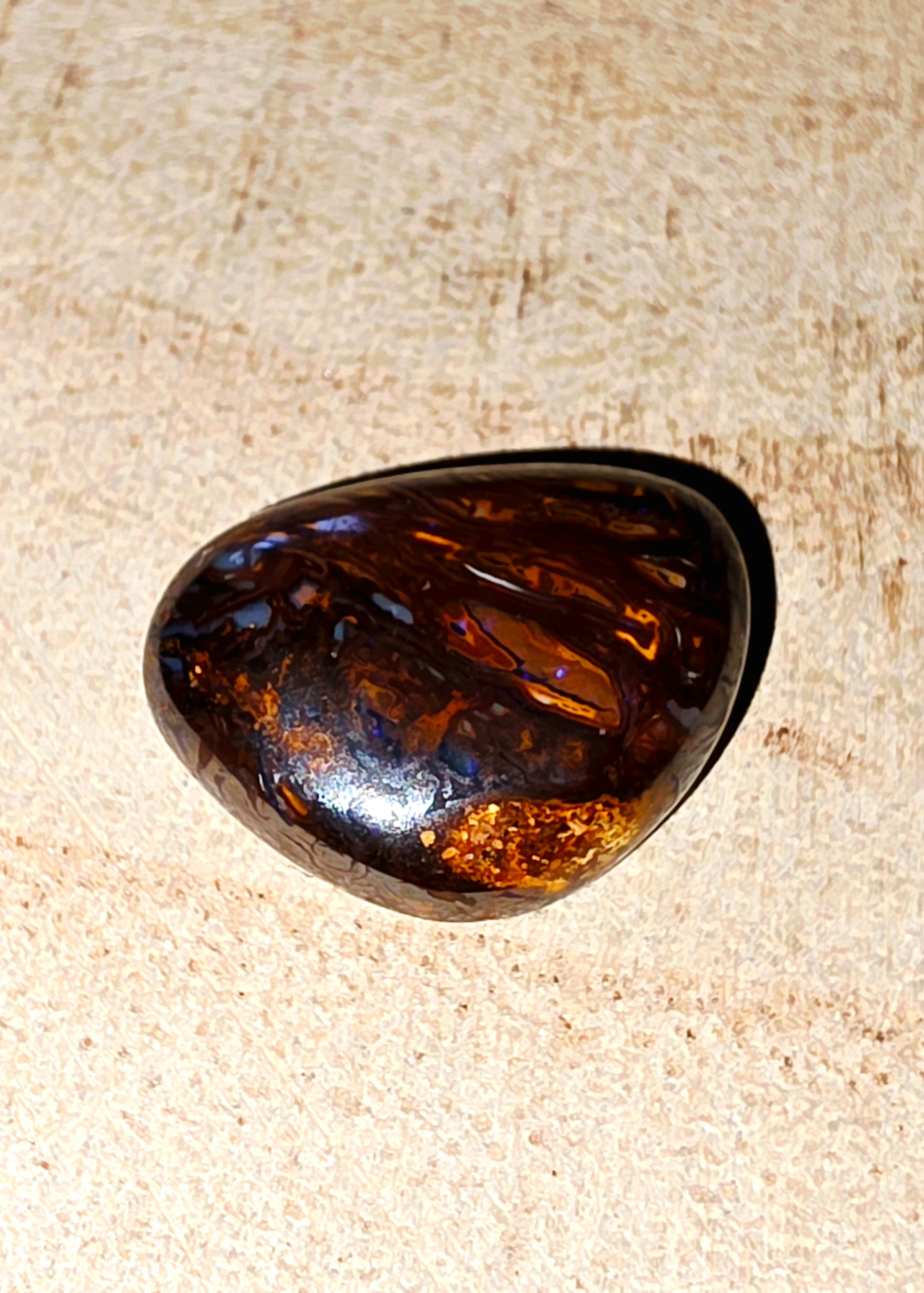 Brown and black opal stone on a beige fabric background