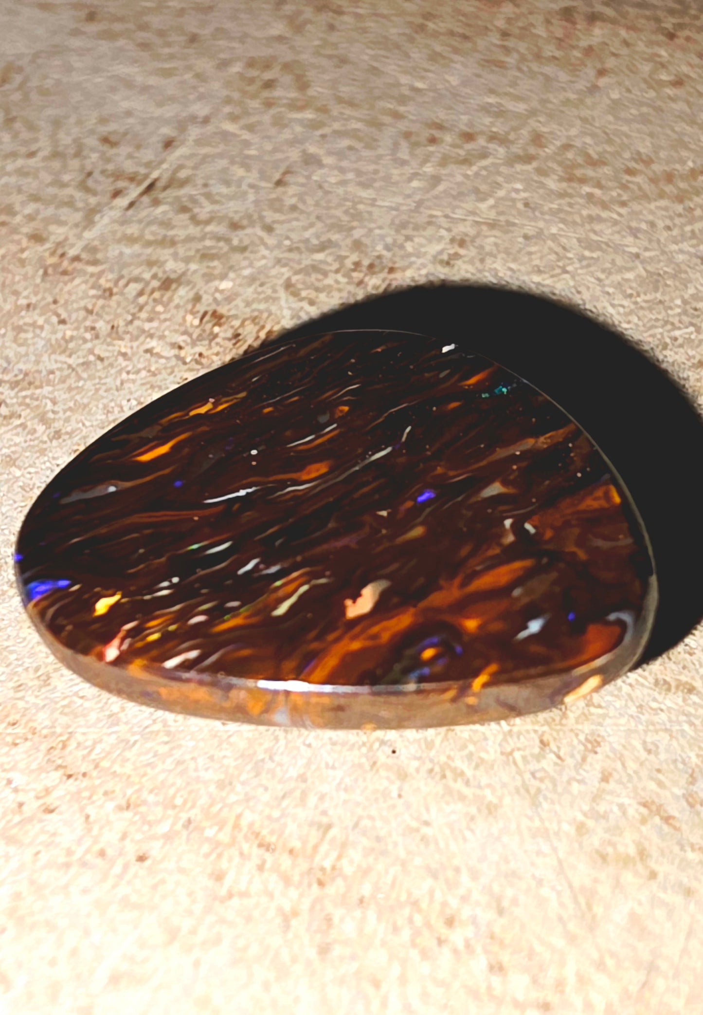 Tortoiseshell-patterned boulder opal on a textured surface