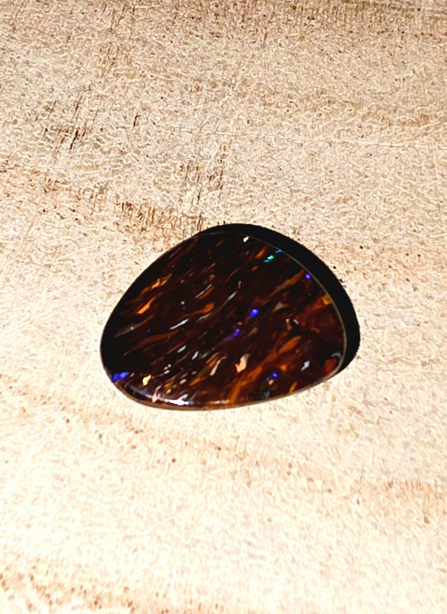 Tortoiseshell-patterned boulder opal on a textured surface