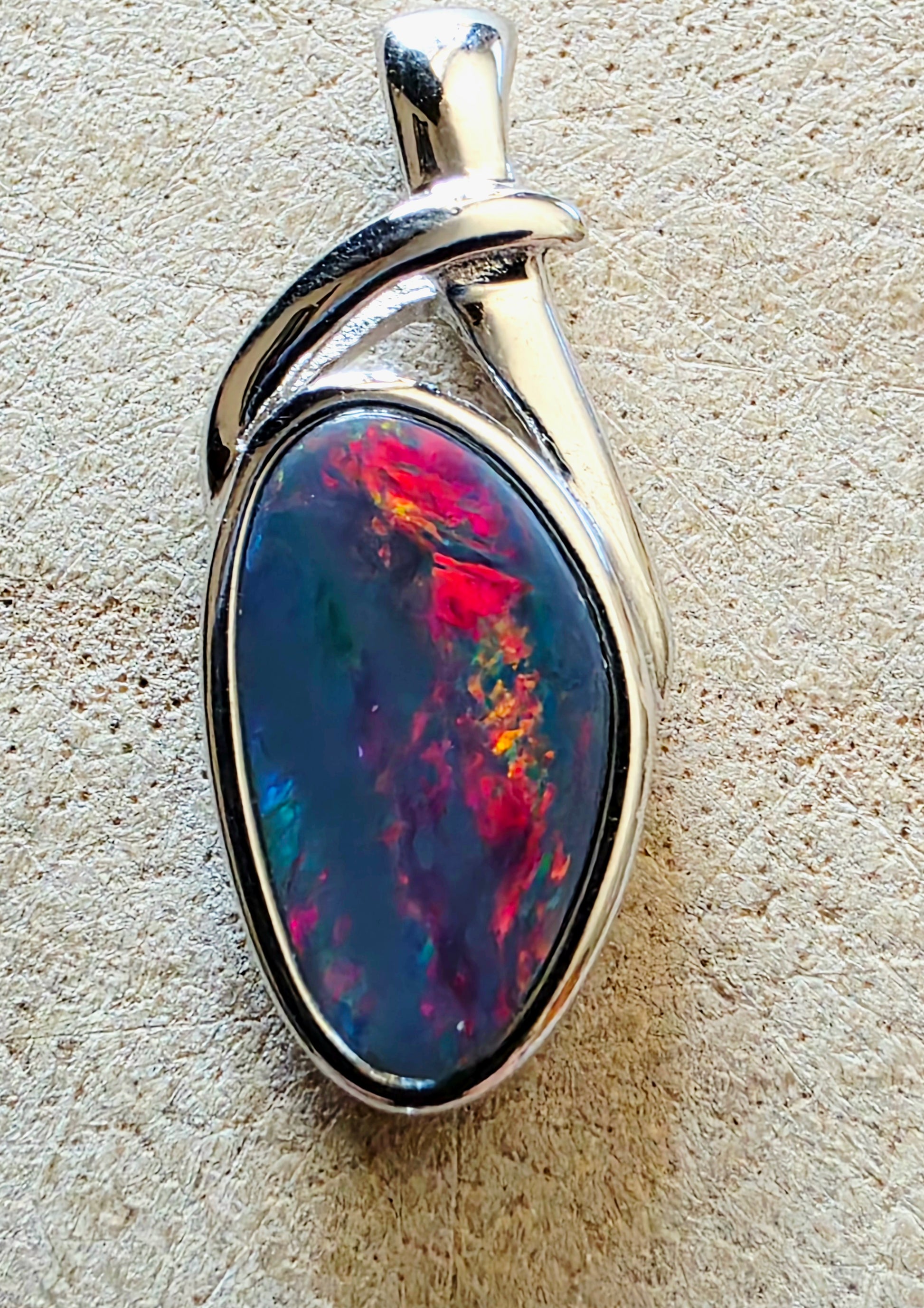 Opal pendant with silver setting on a beige textured background