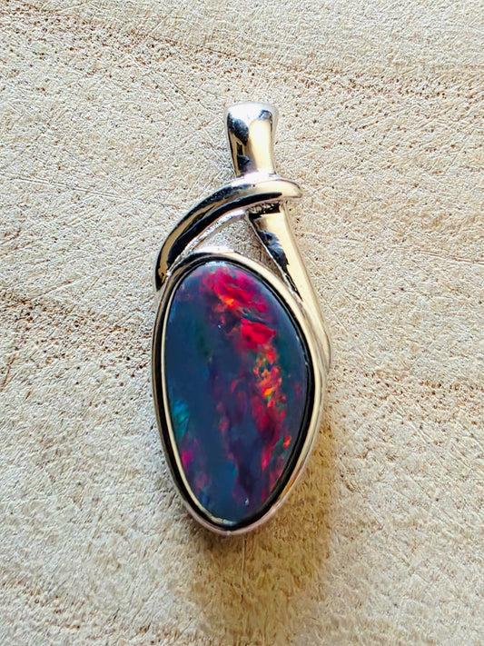 Opal pendant with silver setting on a beige stone background