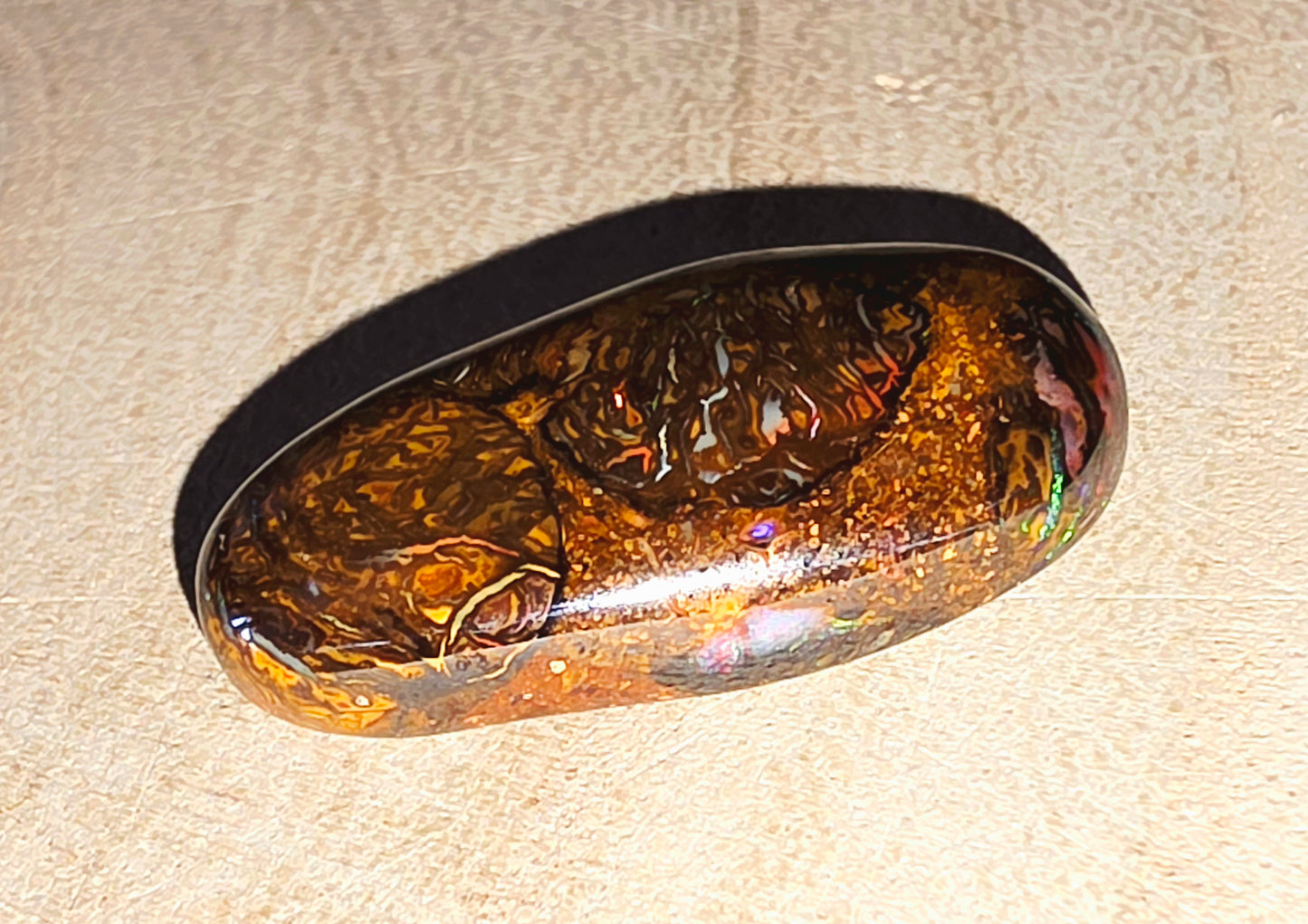 Oval-shaped stone with a reflective surface on a beige background