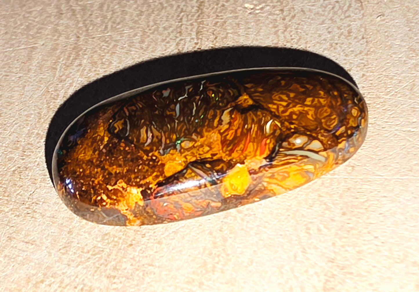 Oval-shaped opal stone inclusion on a beige background