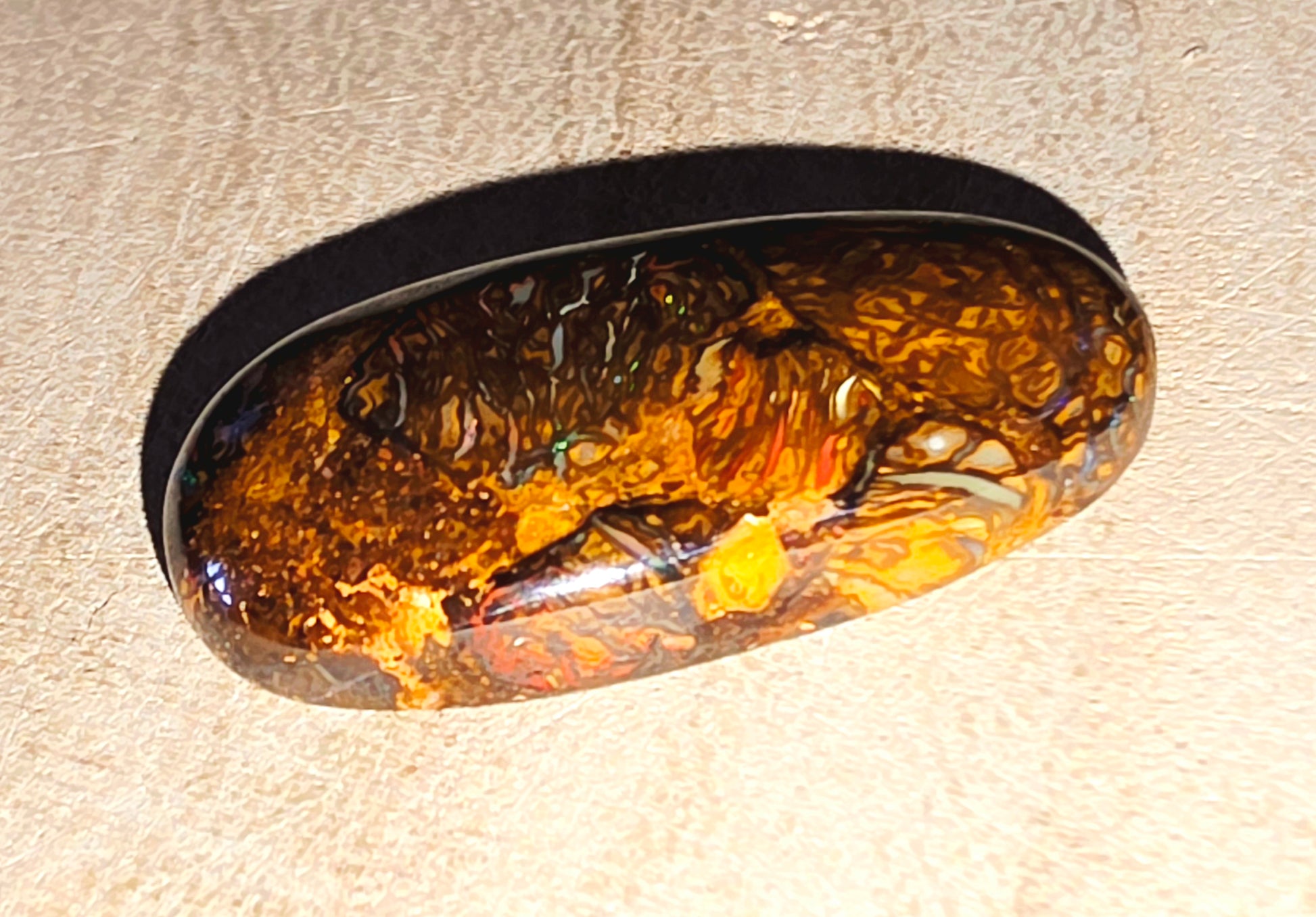 Oval-shaped opal stone inclusion on a beige background