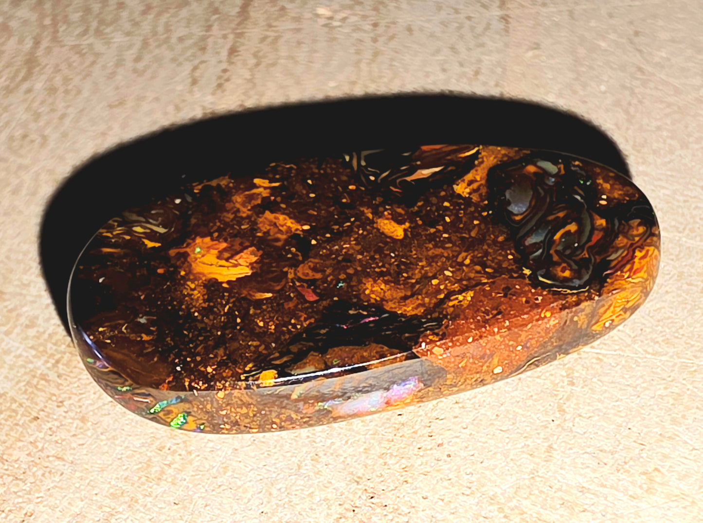 Polished opal stone on a beige surface