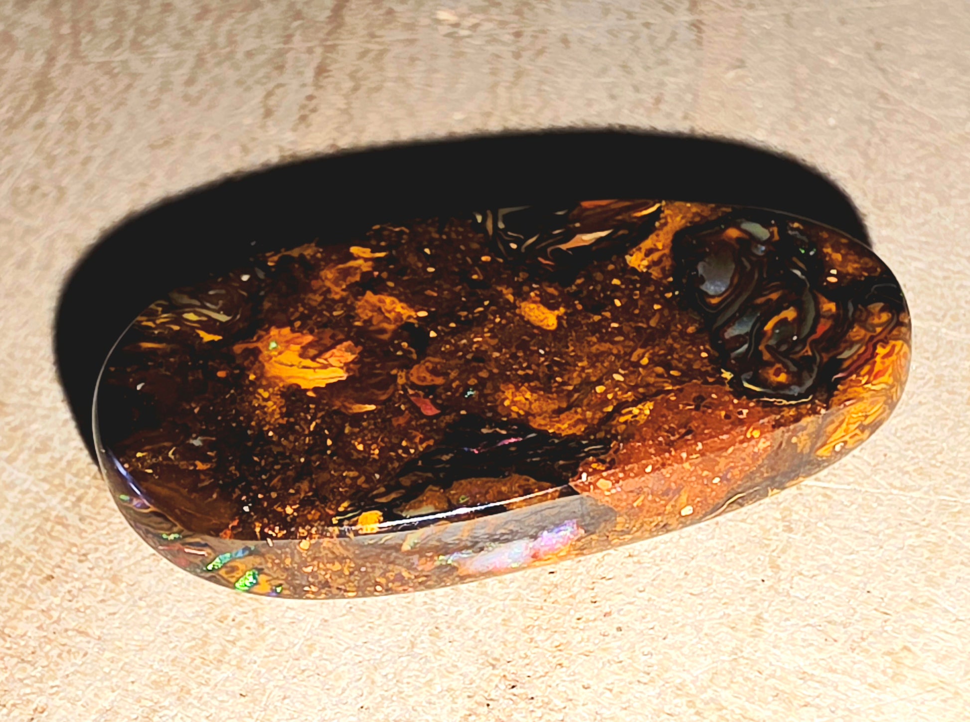 Polished opal stone on a beige surface