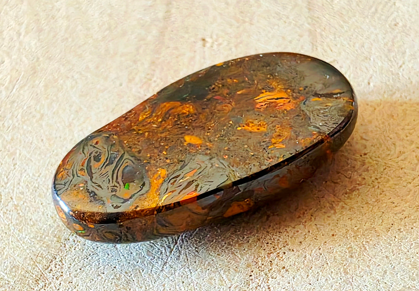 Oval-shaped stone with patterns on a beige surface