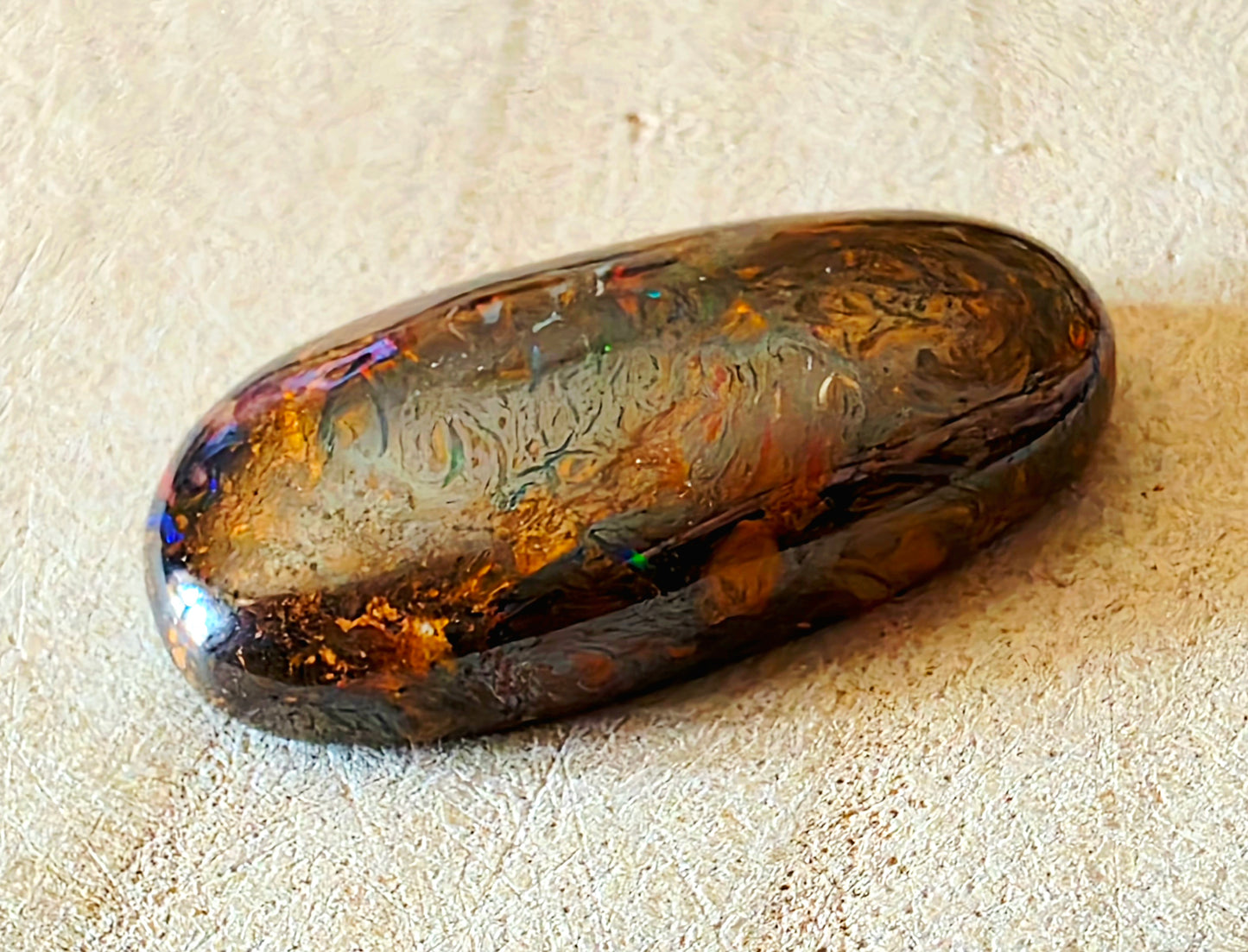 Polished opal stone on a beige surface