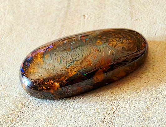 Polished opal stone on a beige surface