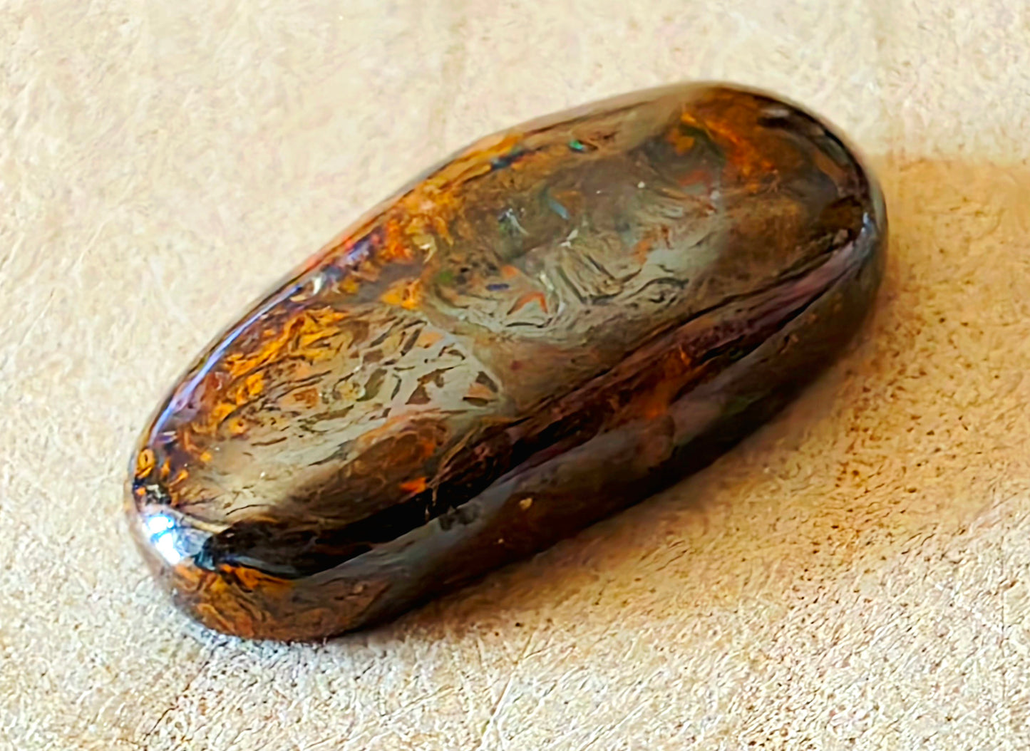 Polished opal stone on a beige surface