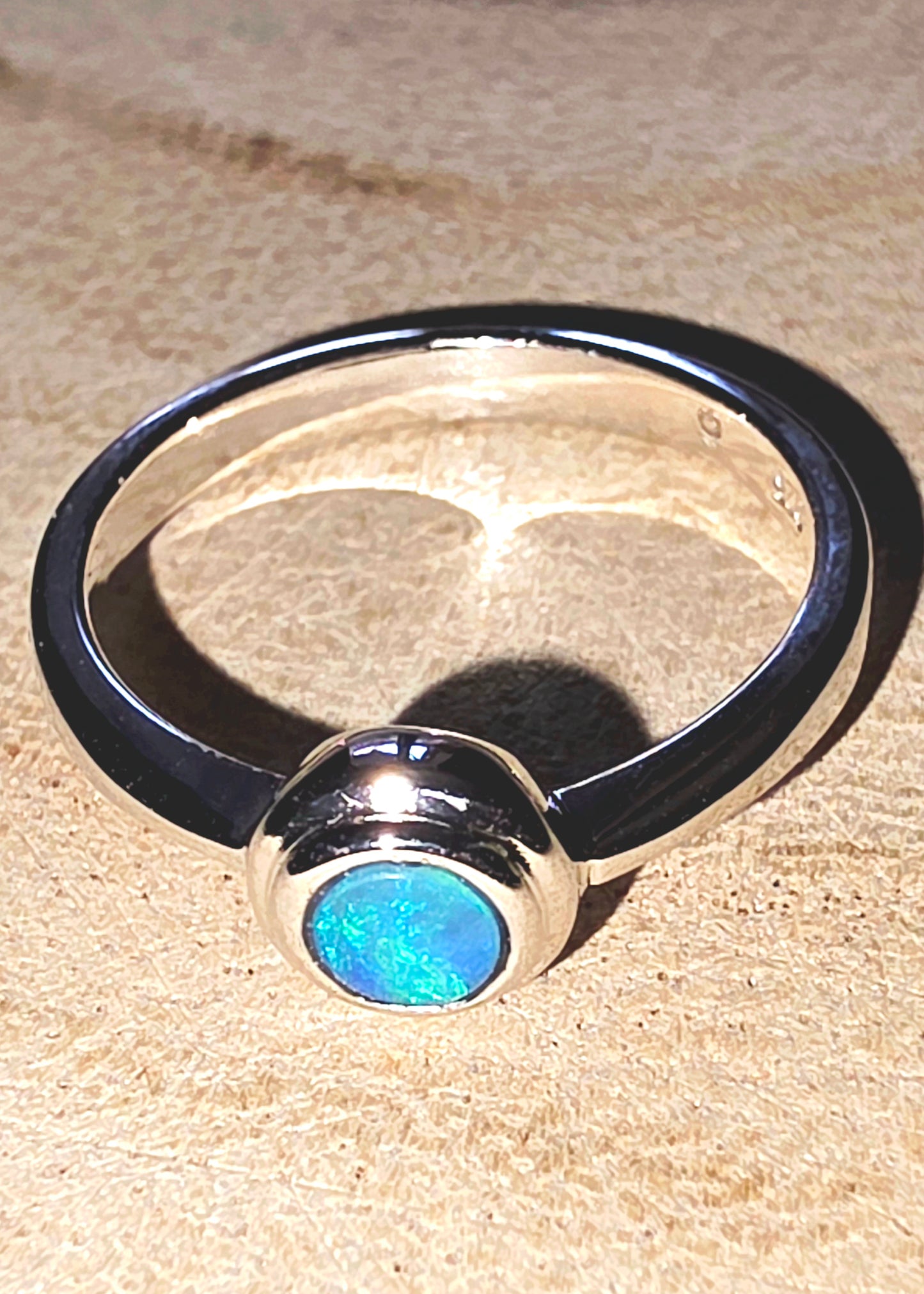 Ring with a blue opal on a beige surface