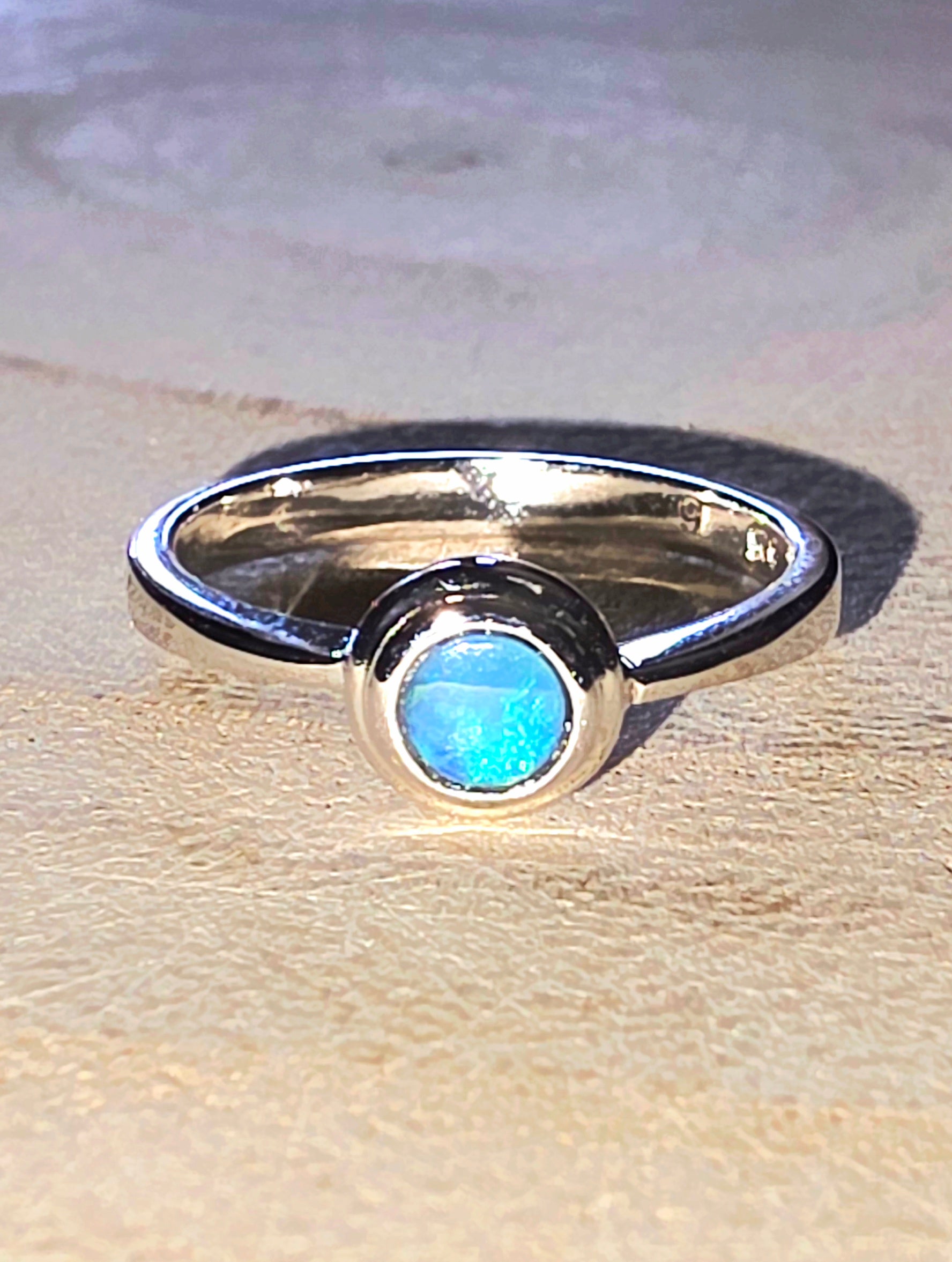 Silver ring with a blue opal on a wooden surface
