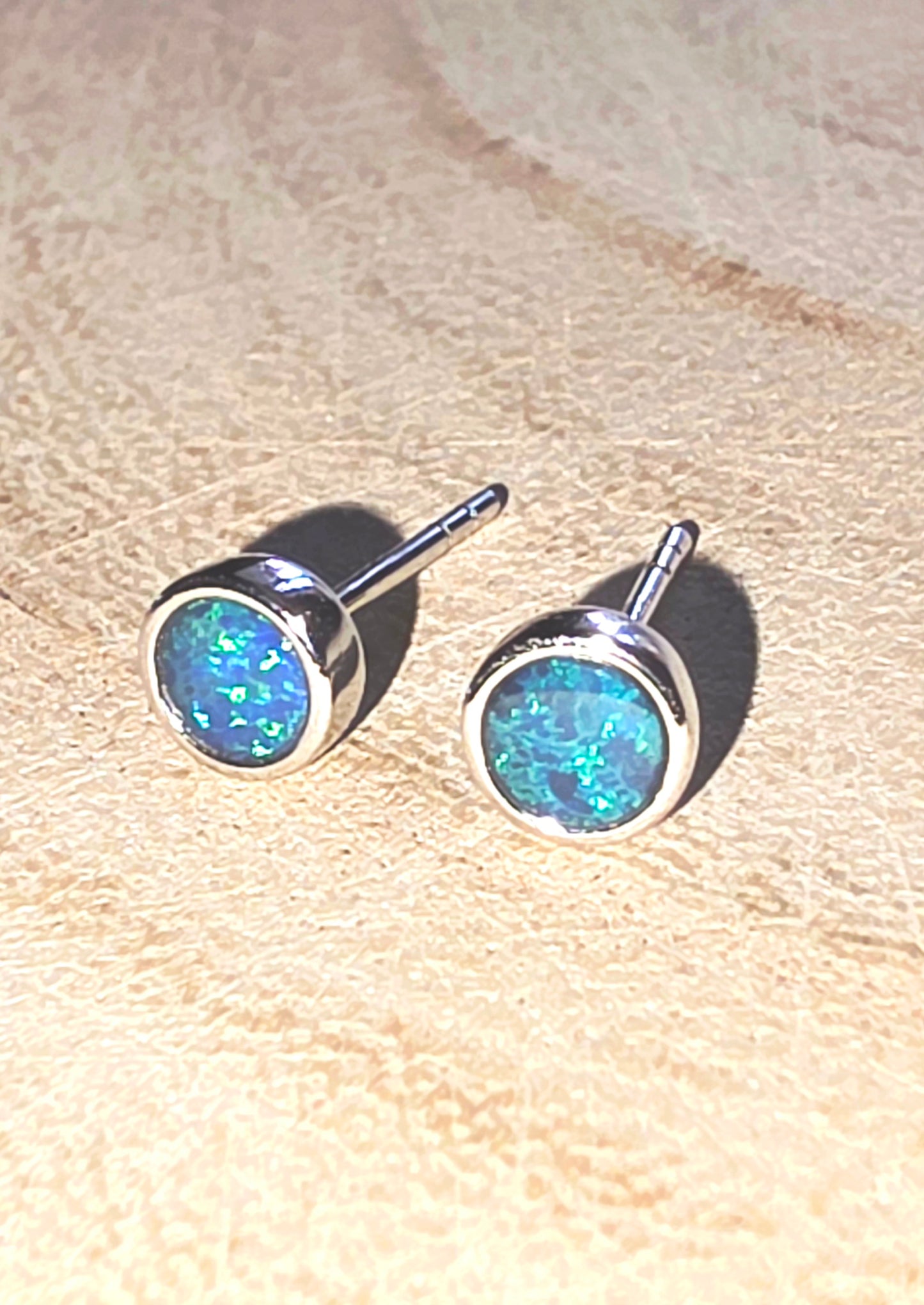 Opal stud earrings on a beige surface