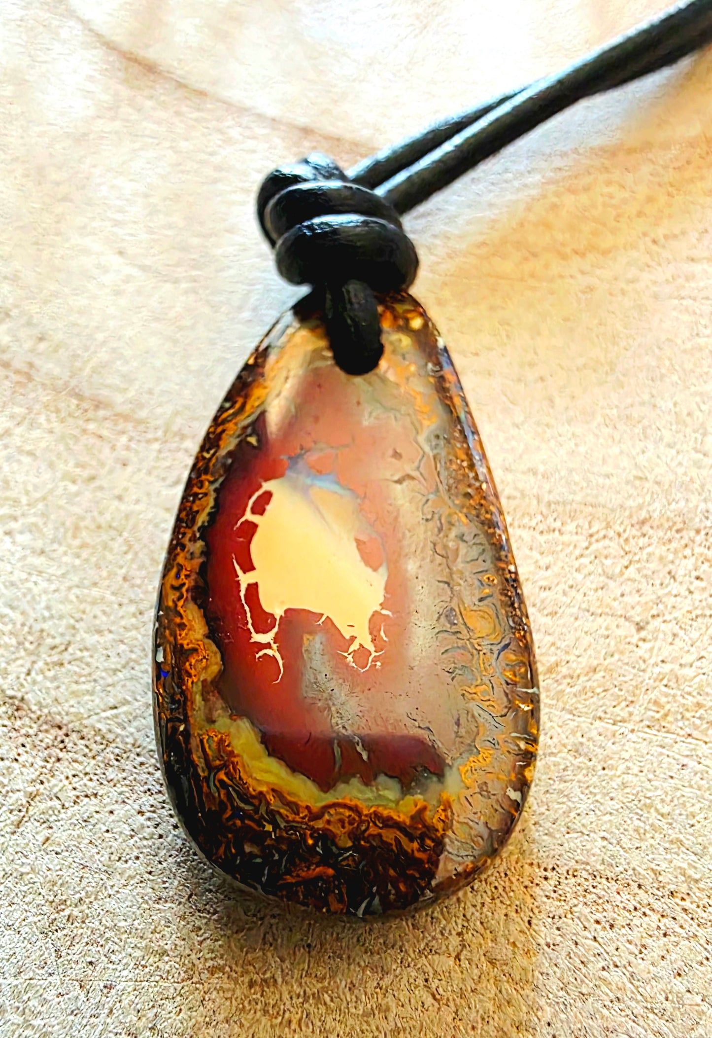 Teardrop-shaped pendant on a beige surface