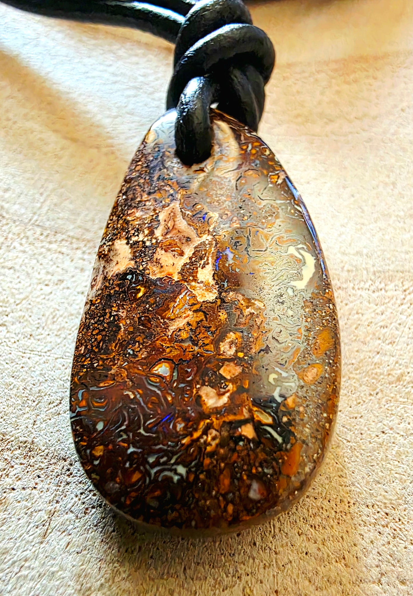 Marbled stone pendant on a leather cord against a beige background