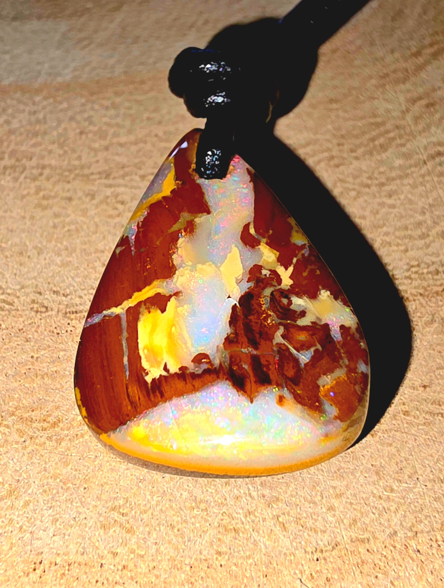 Marbled opal pendant on a beige surface