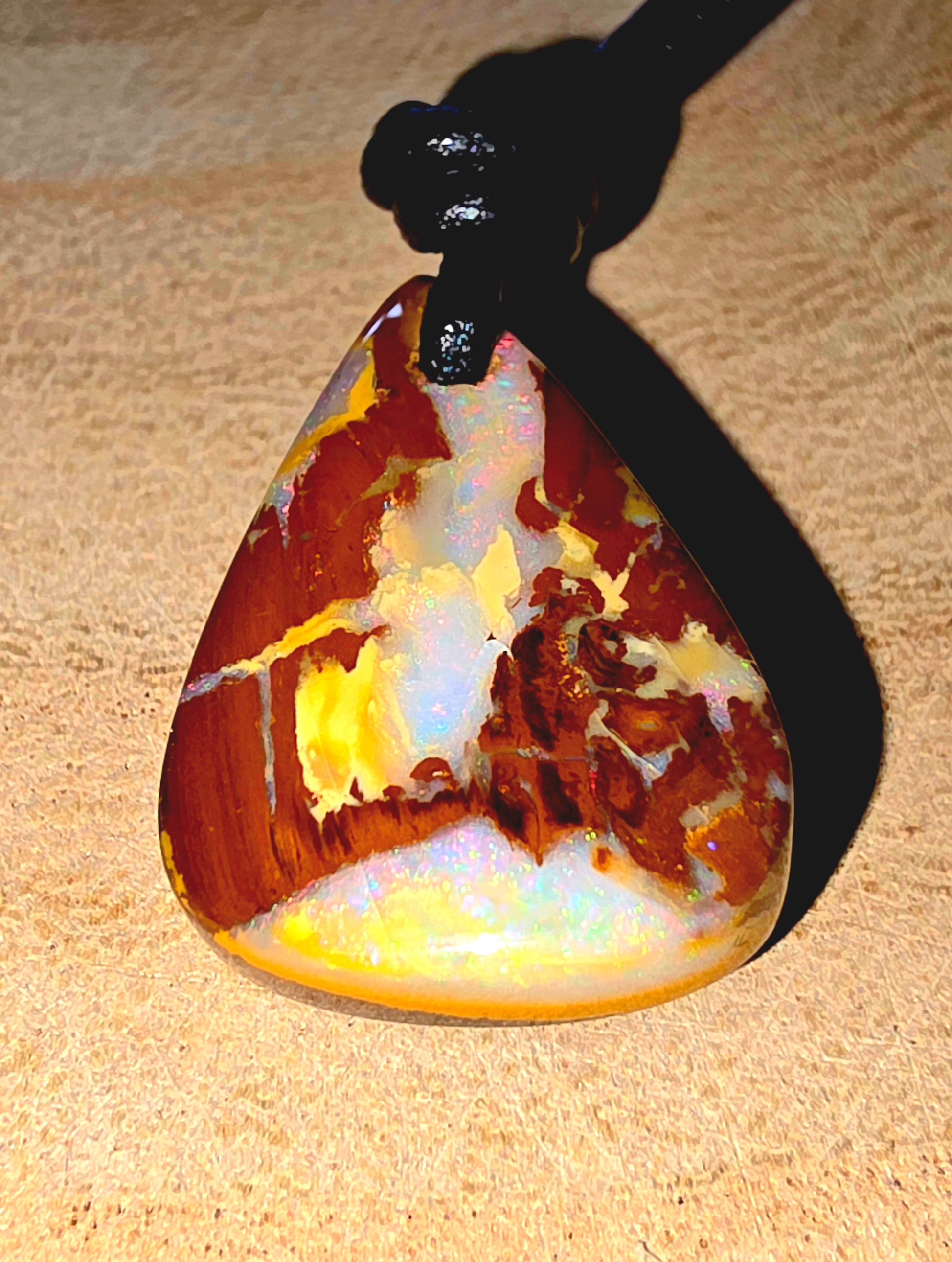 Marbled opal pendant on a beige surface