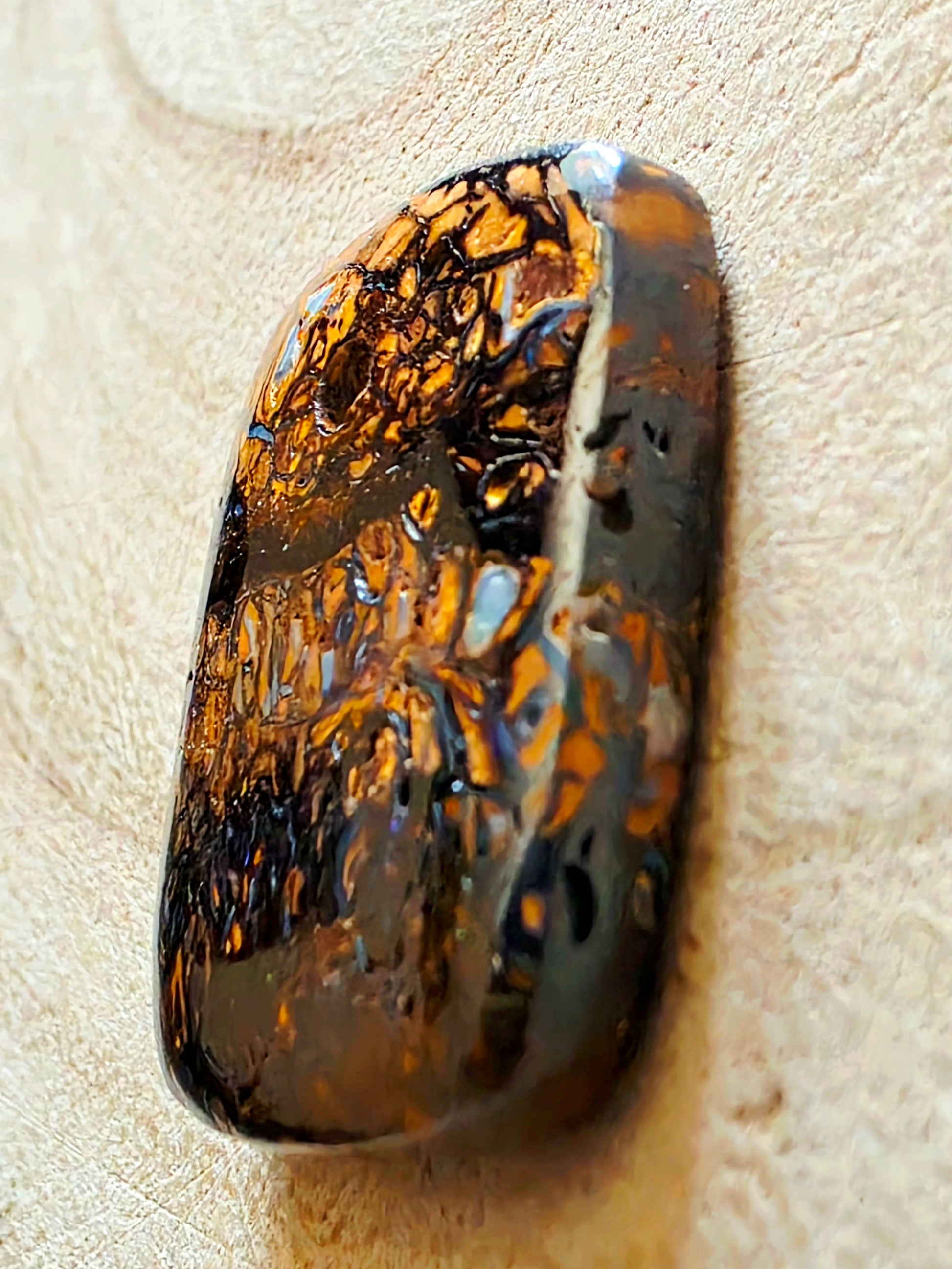 Polished opal stone on a beige background