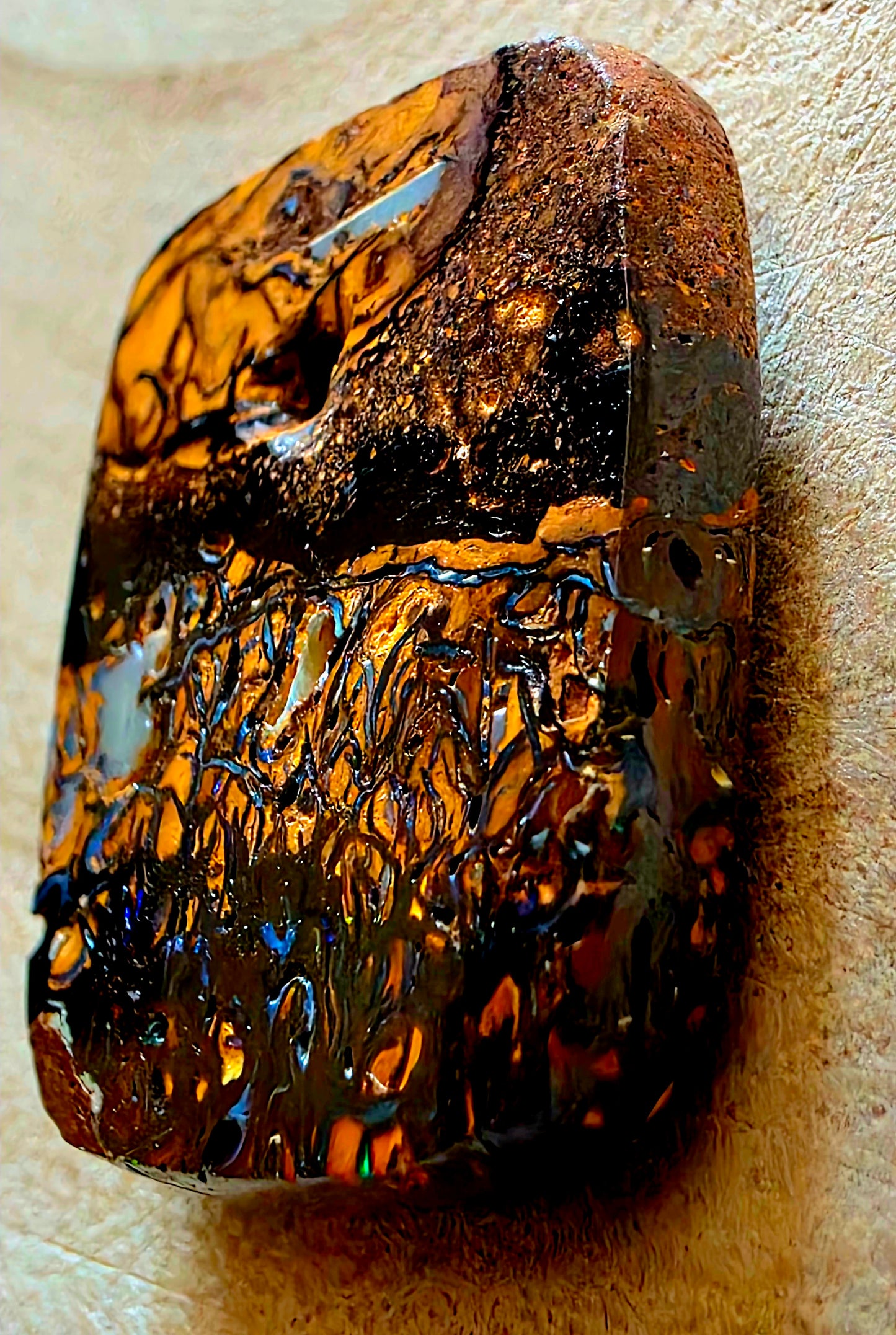 Polished opal stone with intricate patterns on a beige background