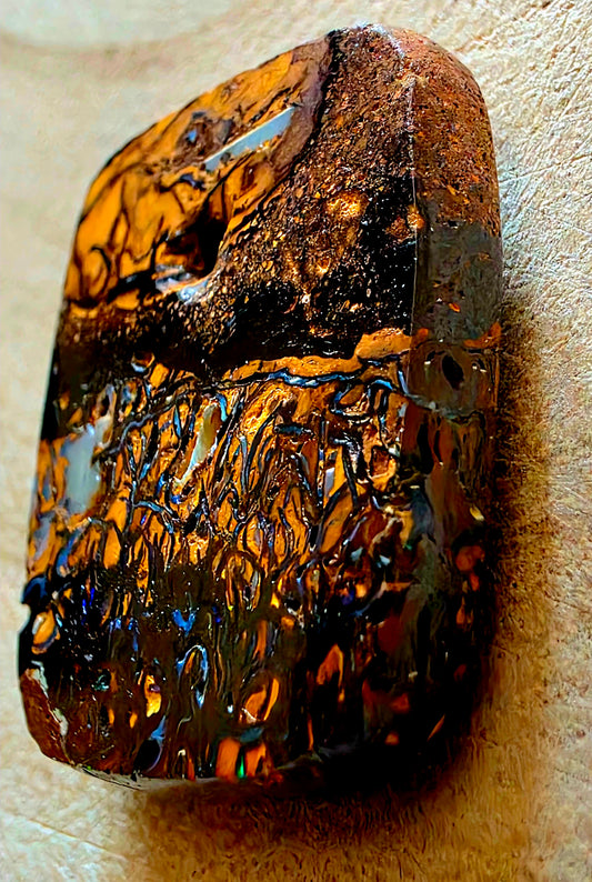 Polished opal stone with intricate patterns on a beige background